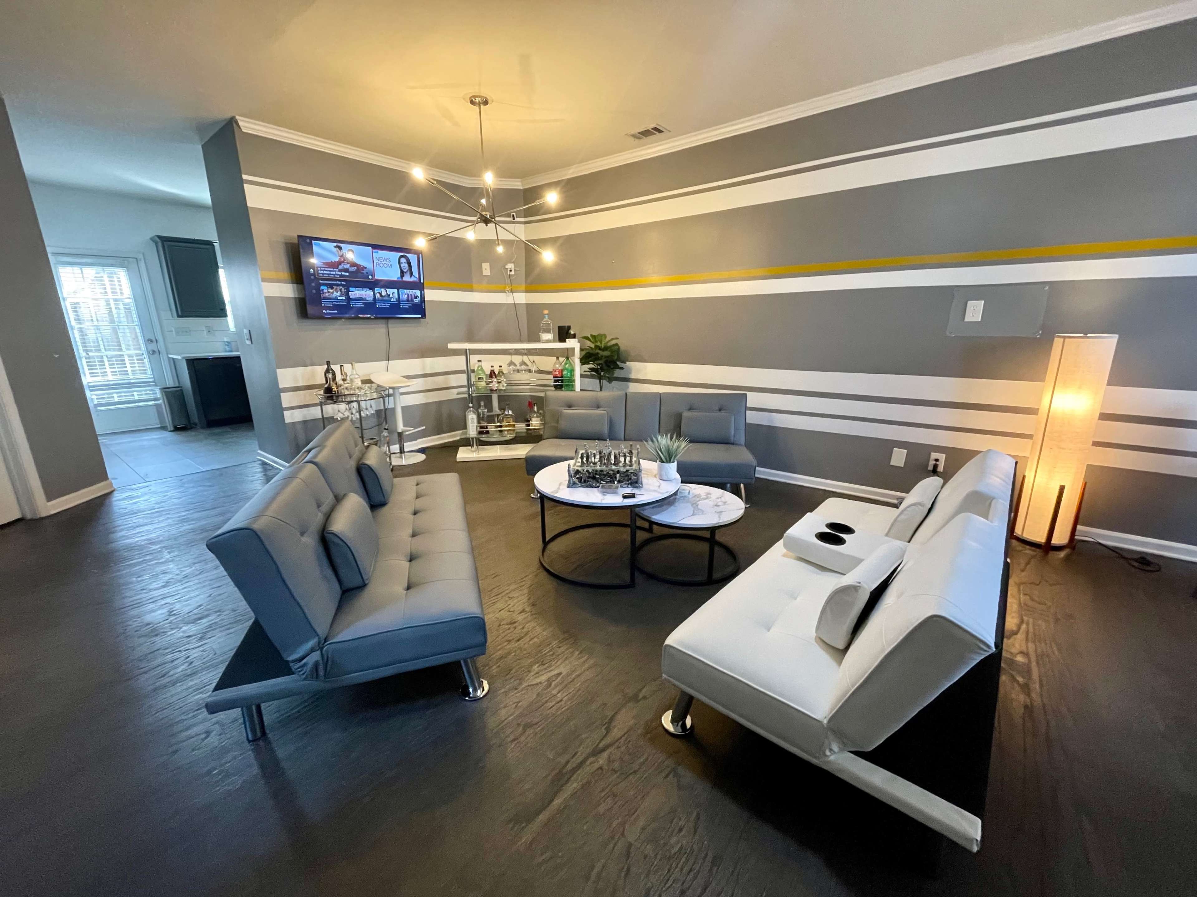 A modern living room with gray walls, two distinct couches, a round coffee table, and a television on the wall.