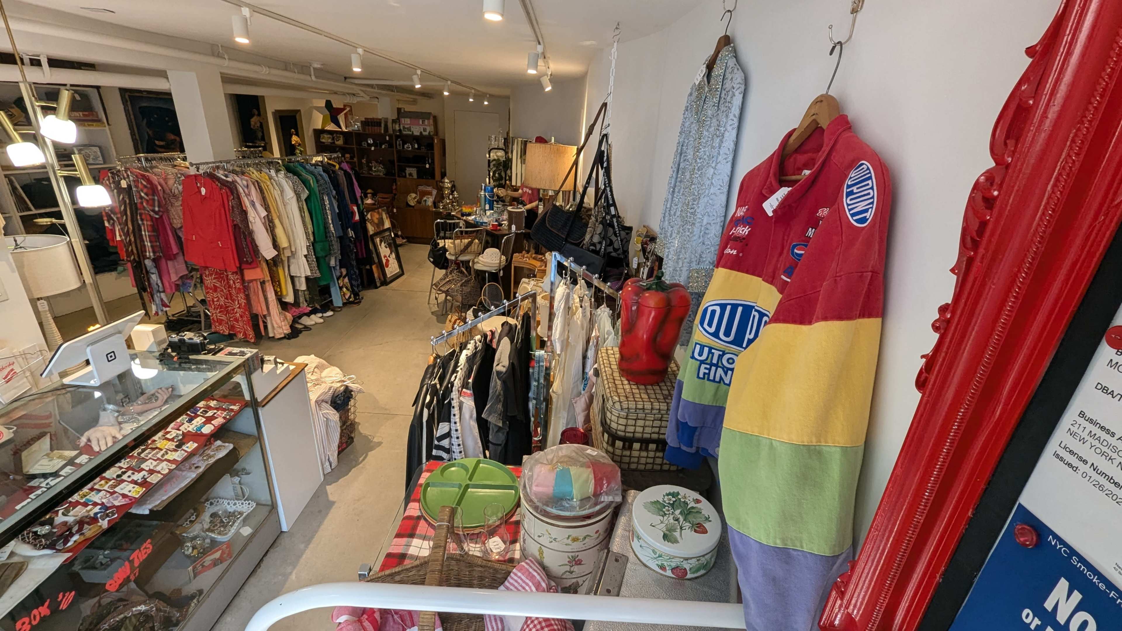 A vintage boutique featuring racks of clothing, accessories, and various decorative items arranged along the walls and aisles.
