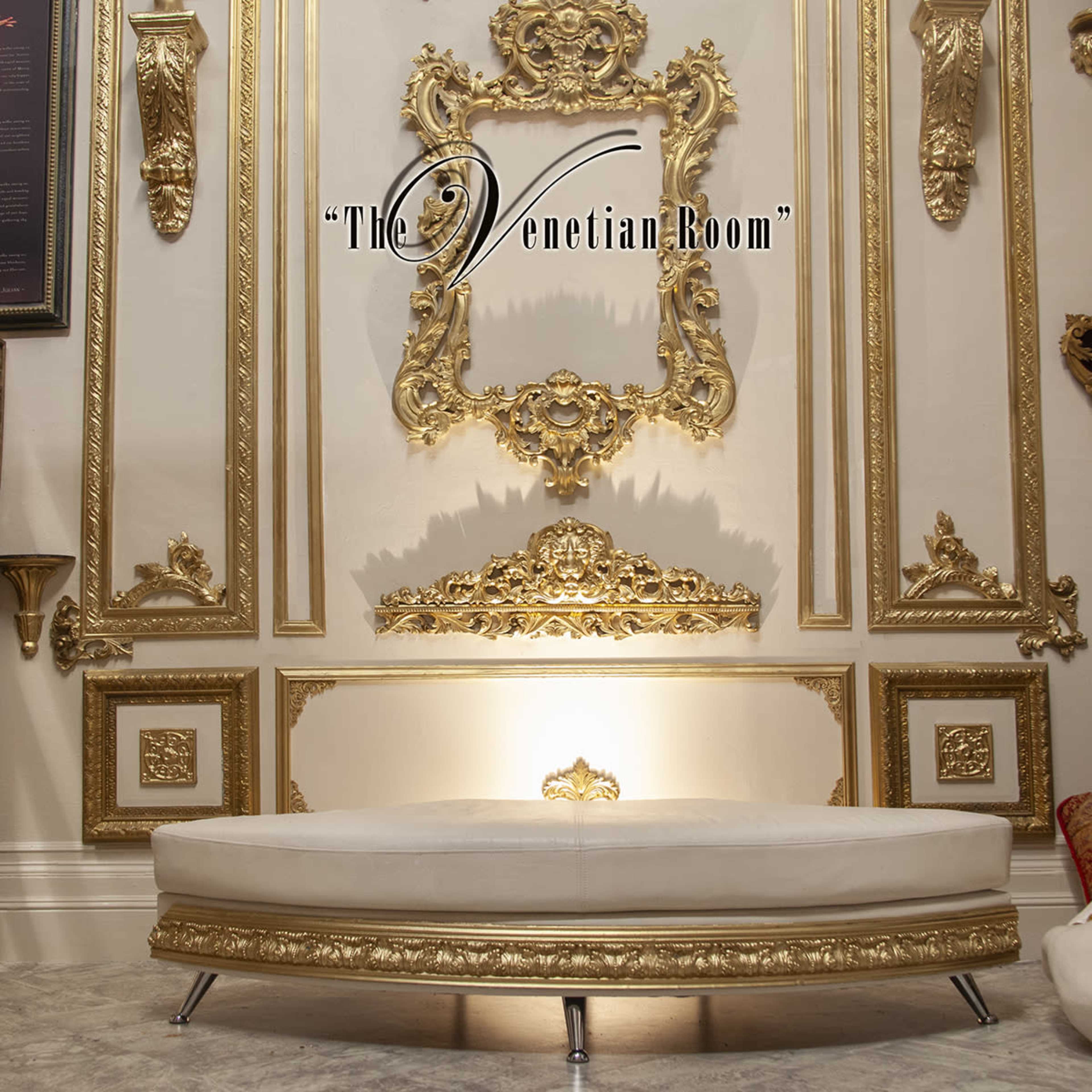 The image features an ornate, gold-framed wall with intricate moldings and a white, curved sofa positioned in front.