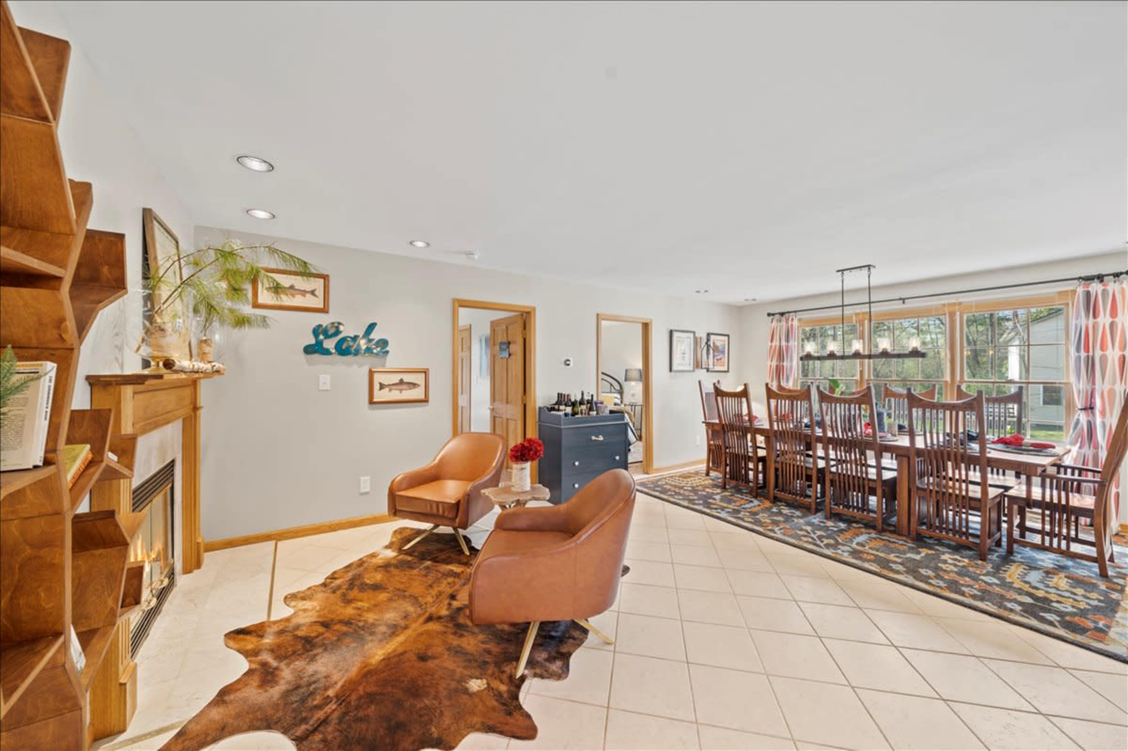 A living area that features a pair of brown chairs, a dining table with multiple chairs in the background, and a fireplace against one wall.