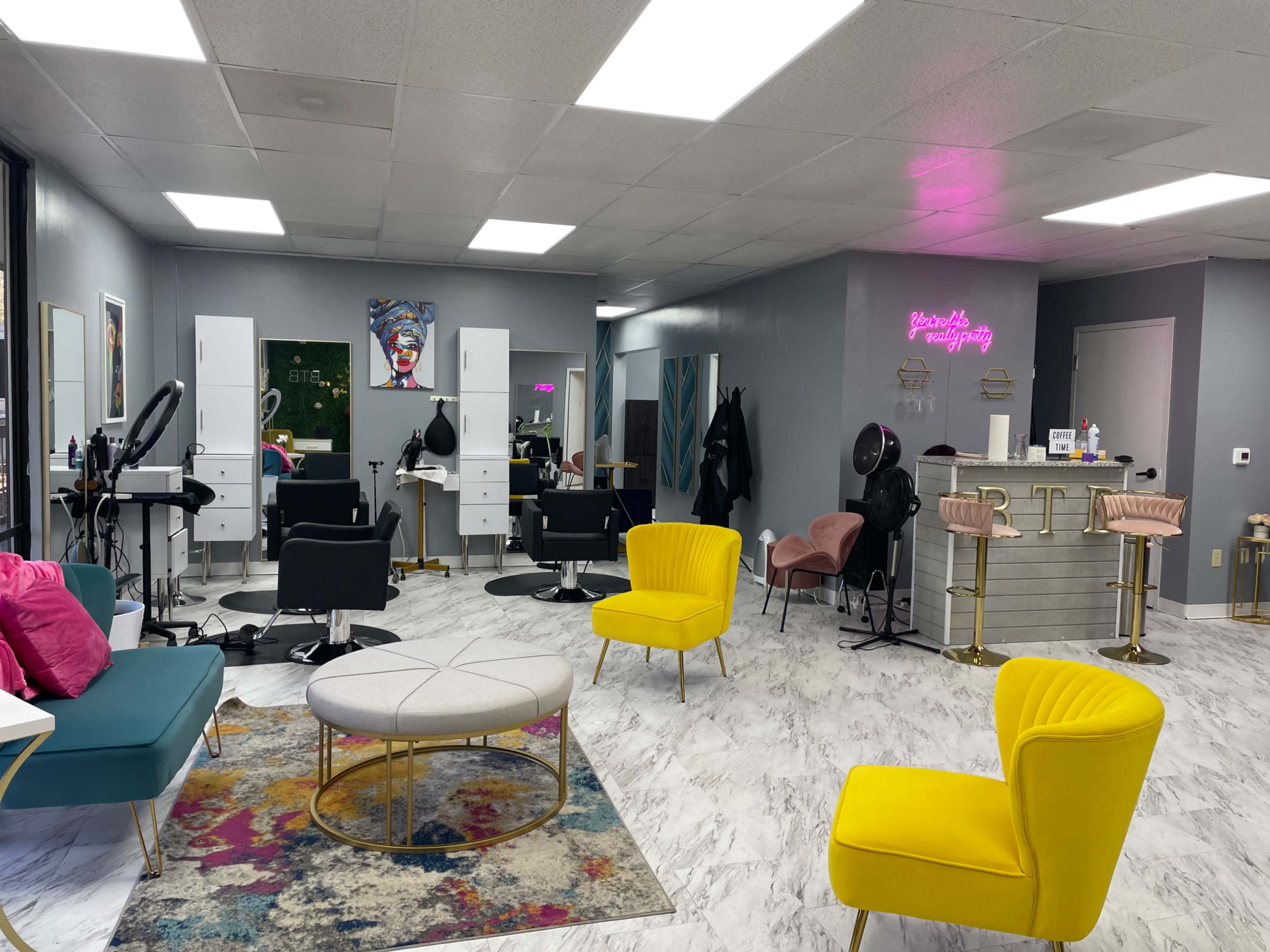 A modern hair salon with sleek styling chairs, bright decor, and vibrant seating arrangements.