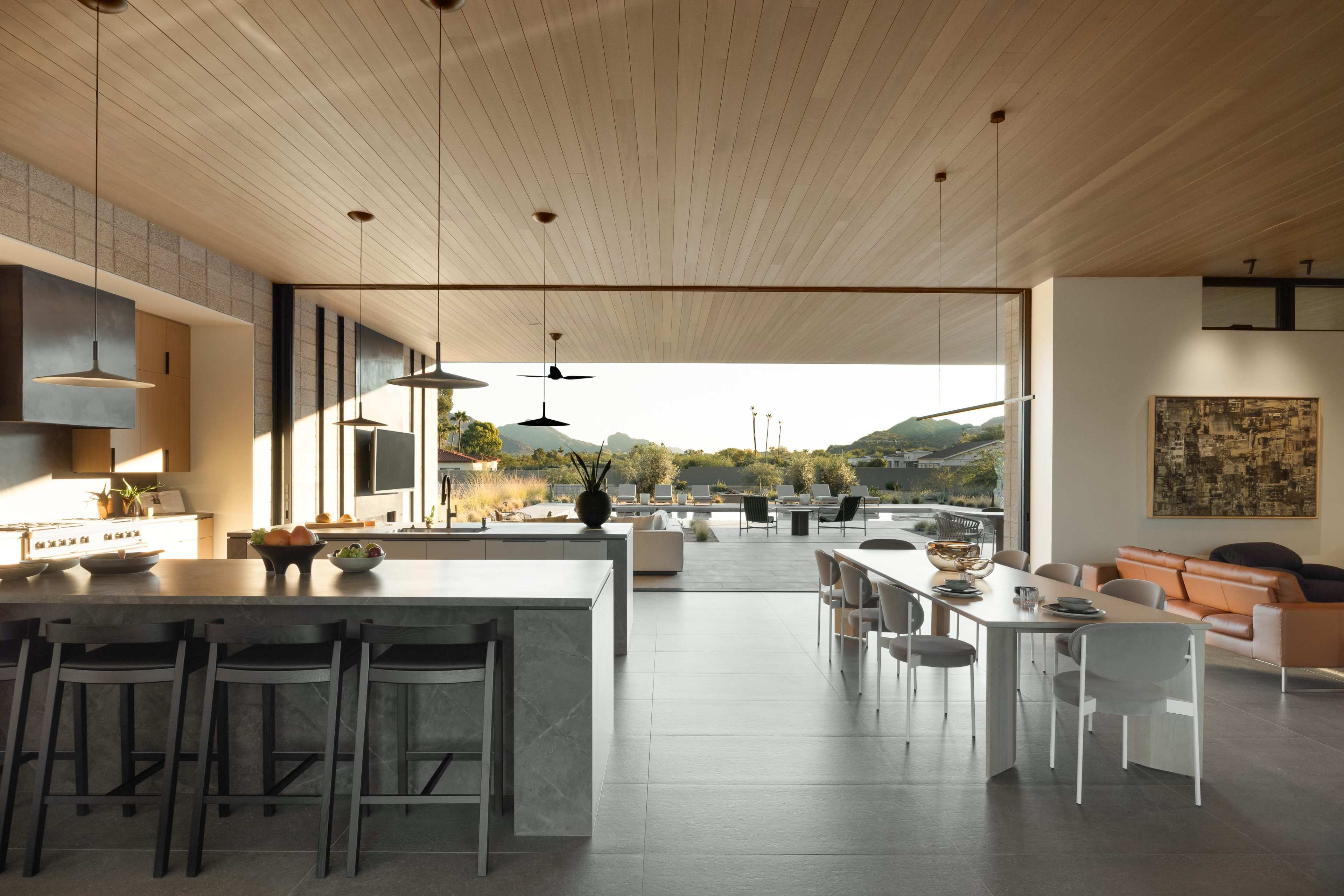 The image shows a modern open-concept kitchen and dining area that seamlessly extends to an outdoor space.