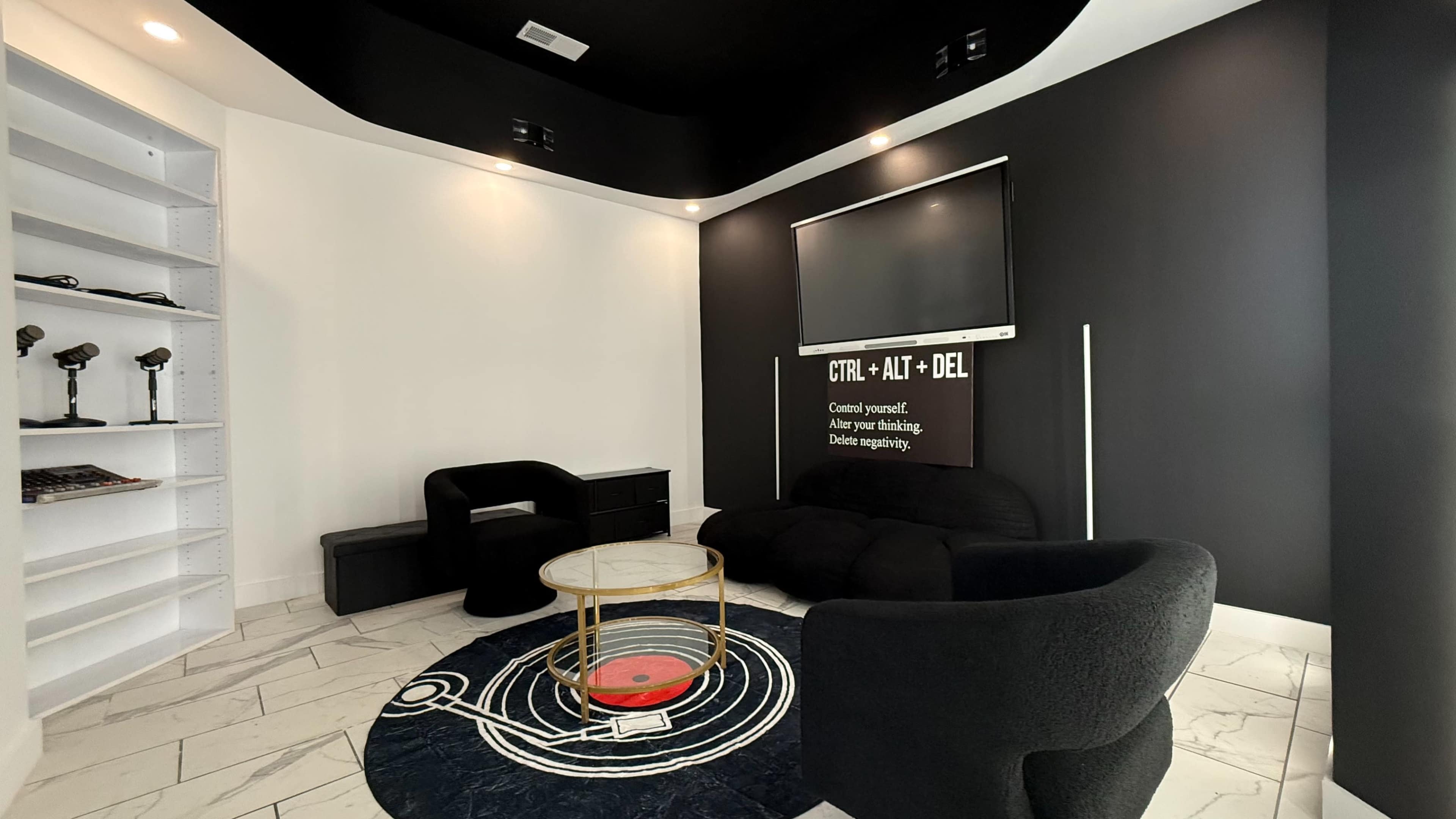 The room features modern furniture, a circular rug, and a wall-mounted television, along with a shelf and artwork displaying tech-themed text.
