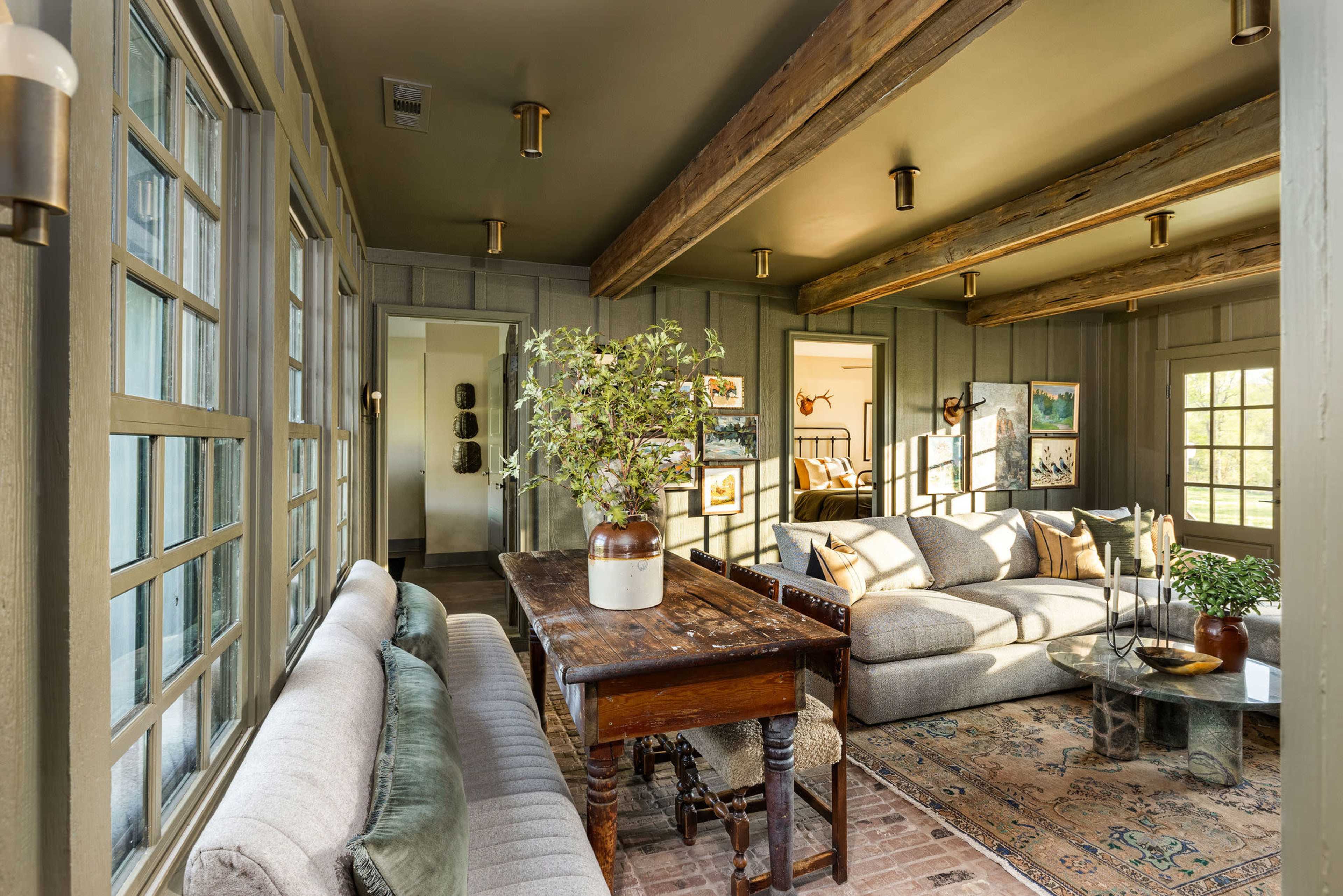 A cozy living room featuring a wooden table, two sofas, and natural light streaming through windows.
