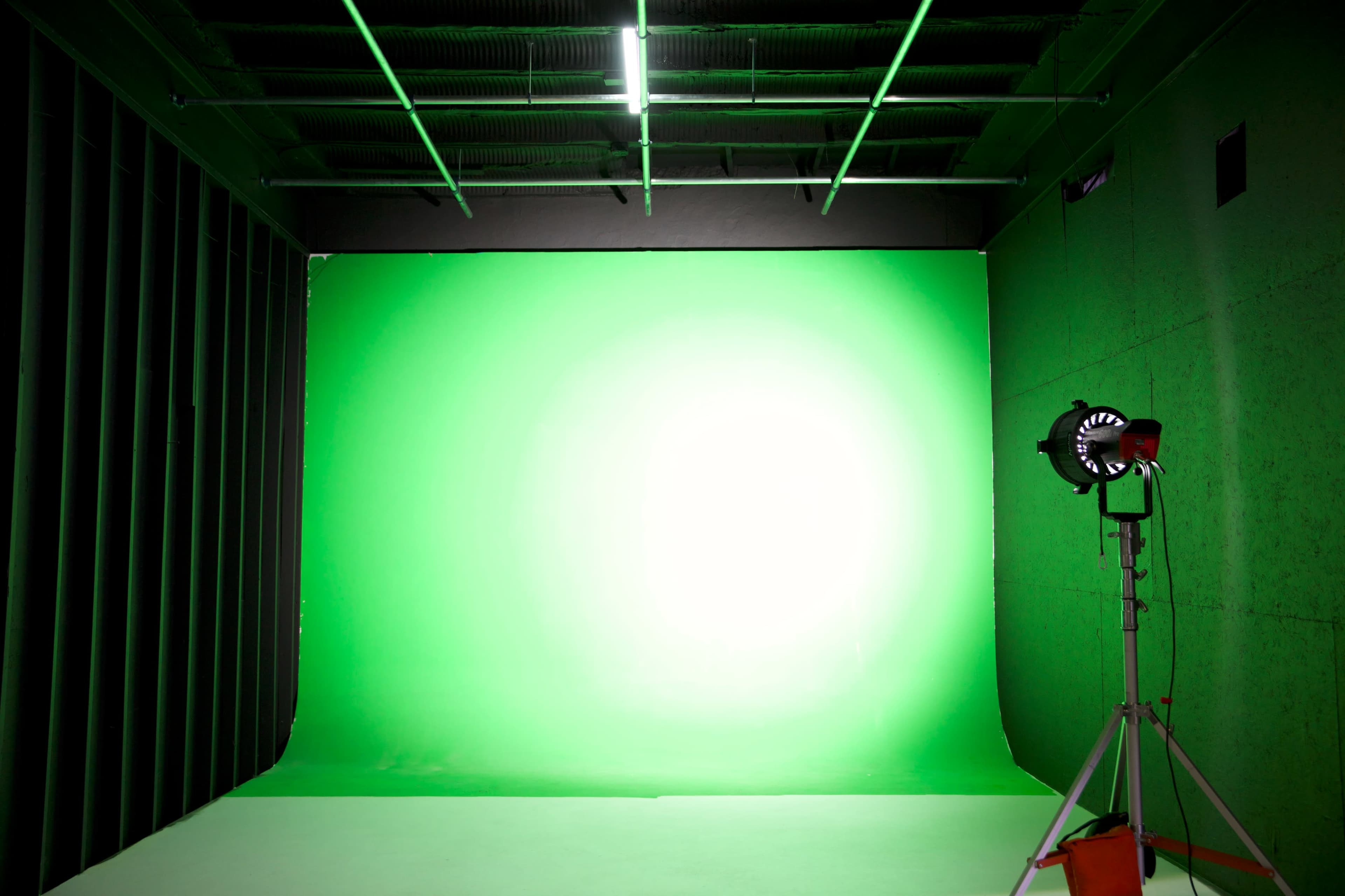 A studio setup with a green backdrop and a spotlight on a stand.