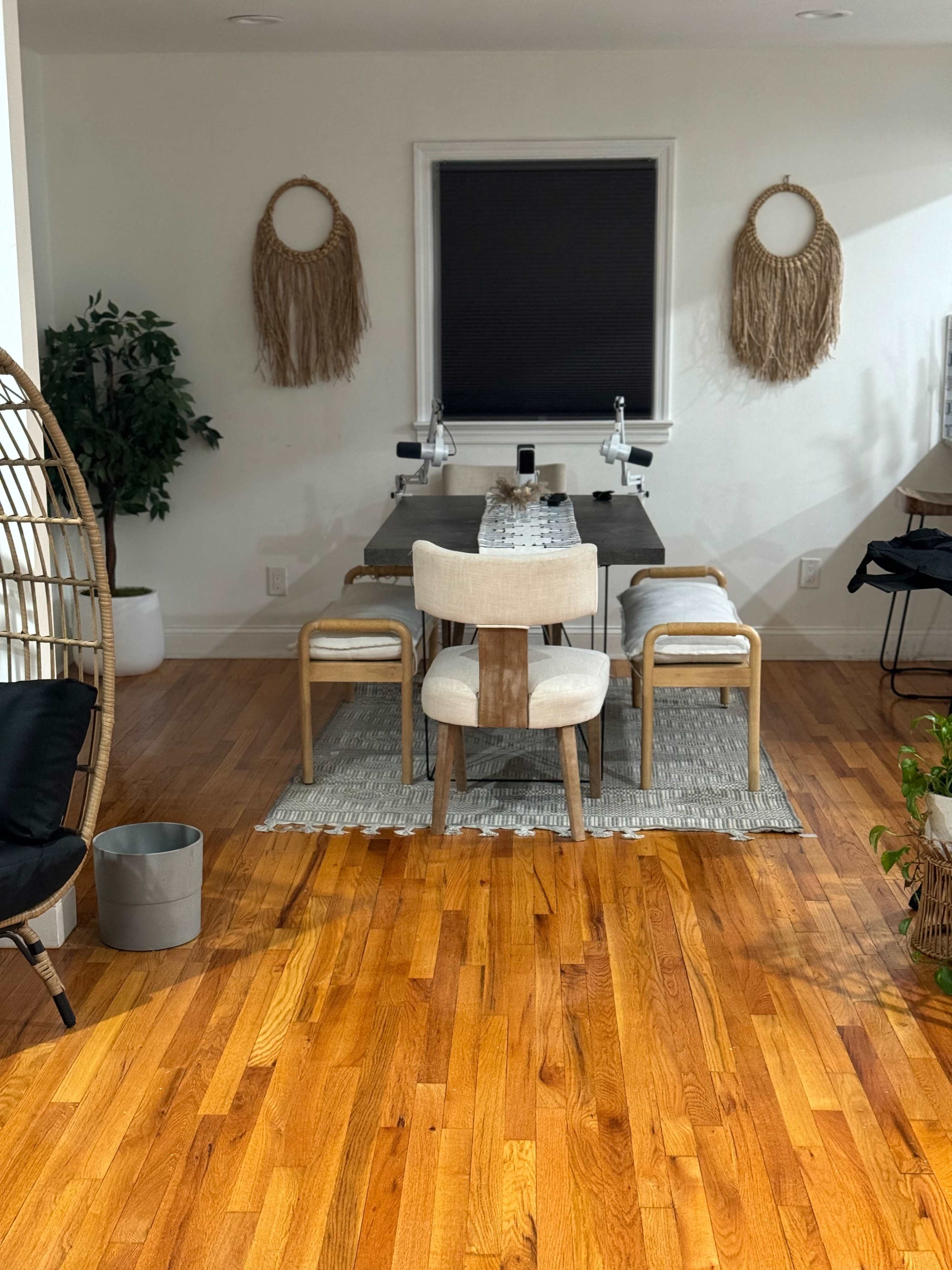 A dining area features a wooden table surrounded by chairs, with decorative wall hangings and plants enhancing the modern decor.