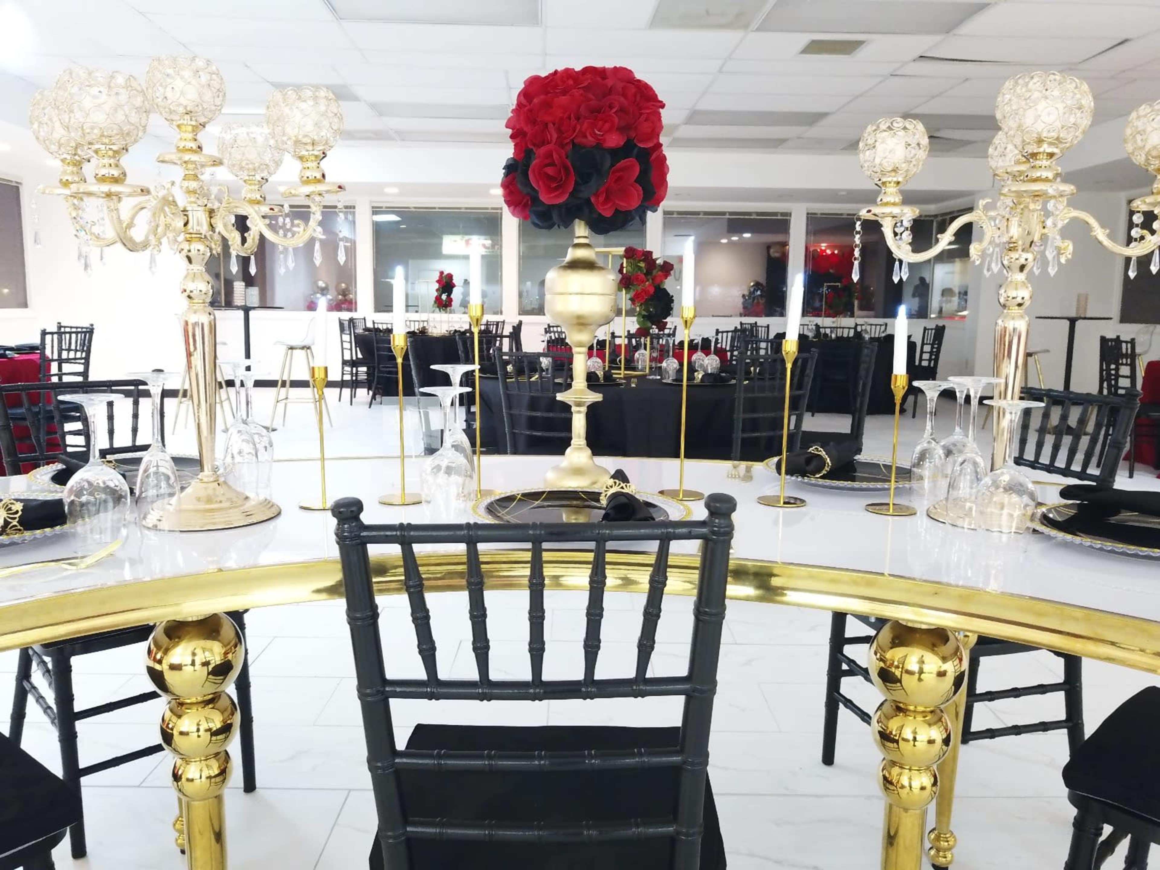 A modern dining area set up for a formal event, featuring elegantly decorated tables with black tablecloths and decorative centerpieces.