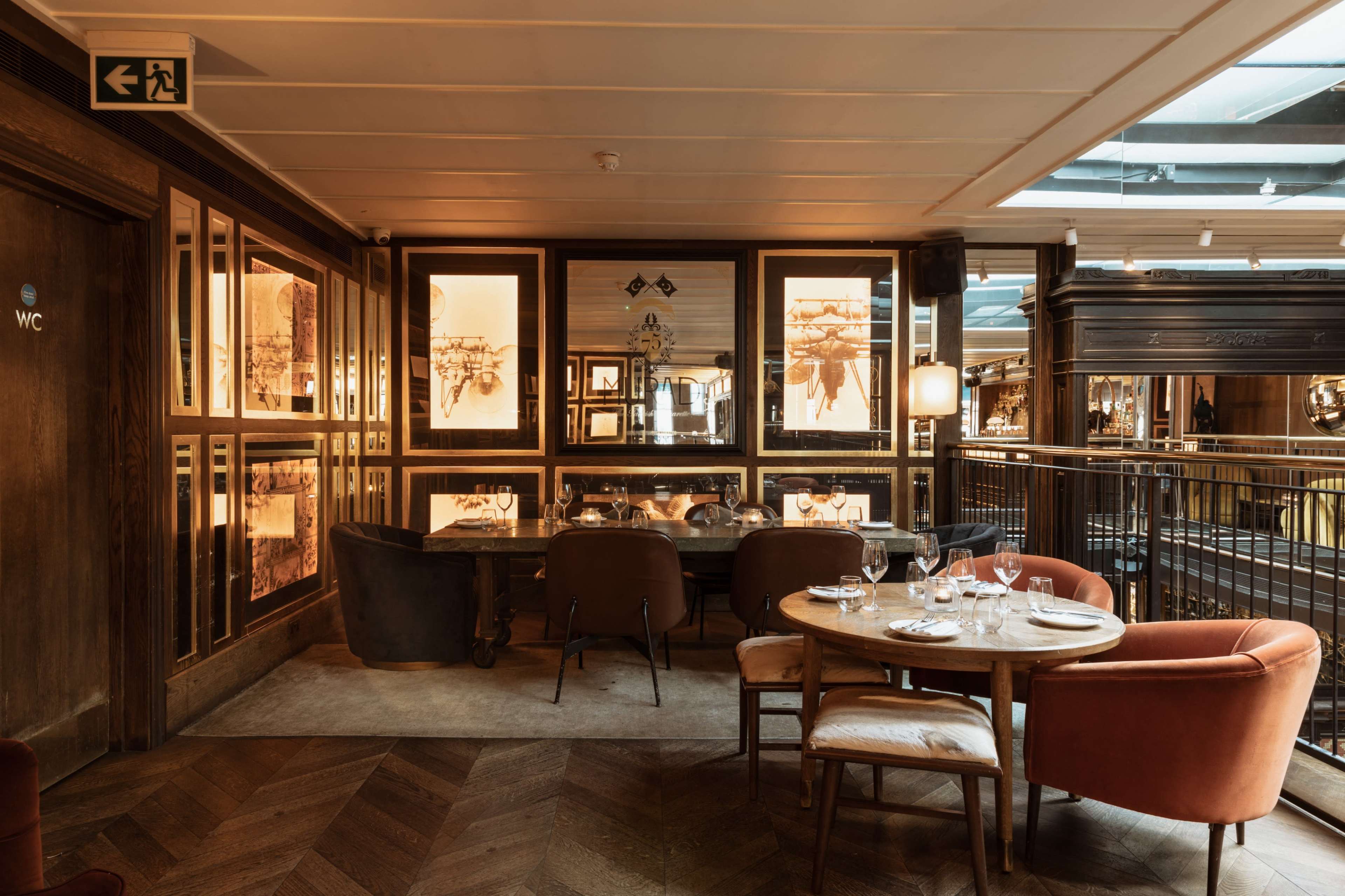 A cozy restaurant interior features wooden accents, elegant seating arrangements, and framed art on the walls.