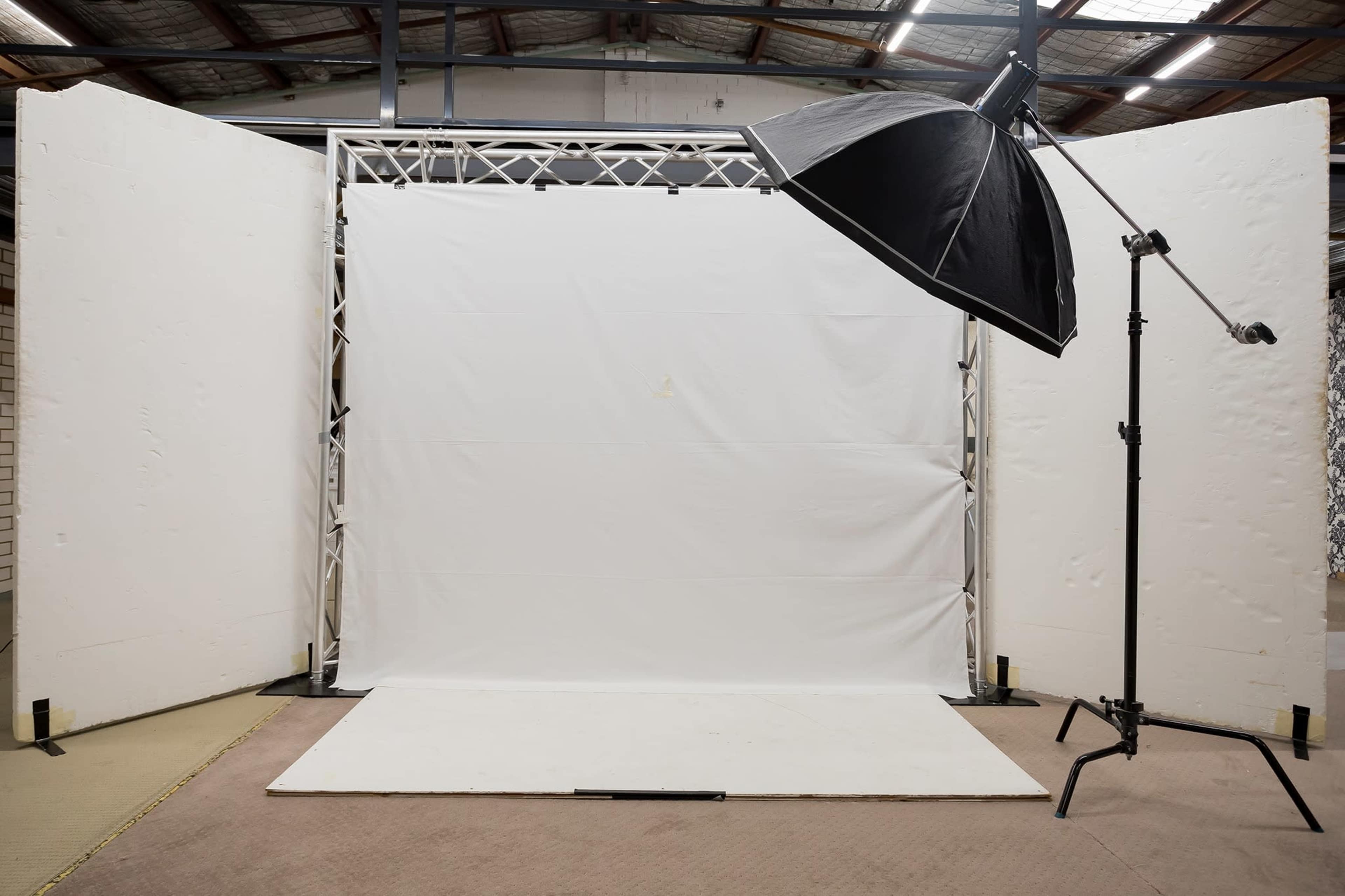A photography studio setup with a white backdrop and a large softbox light positioned at an angle.