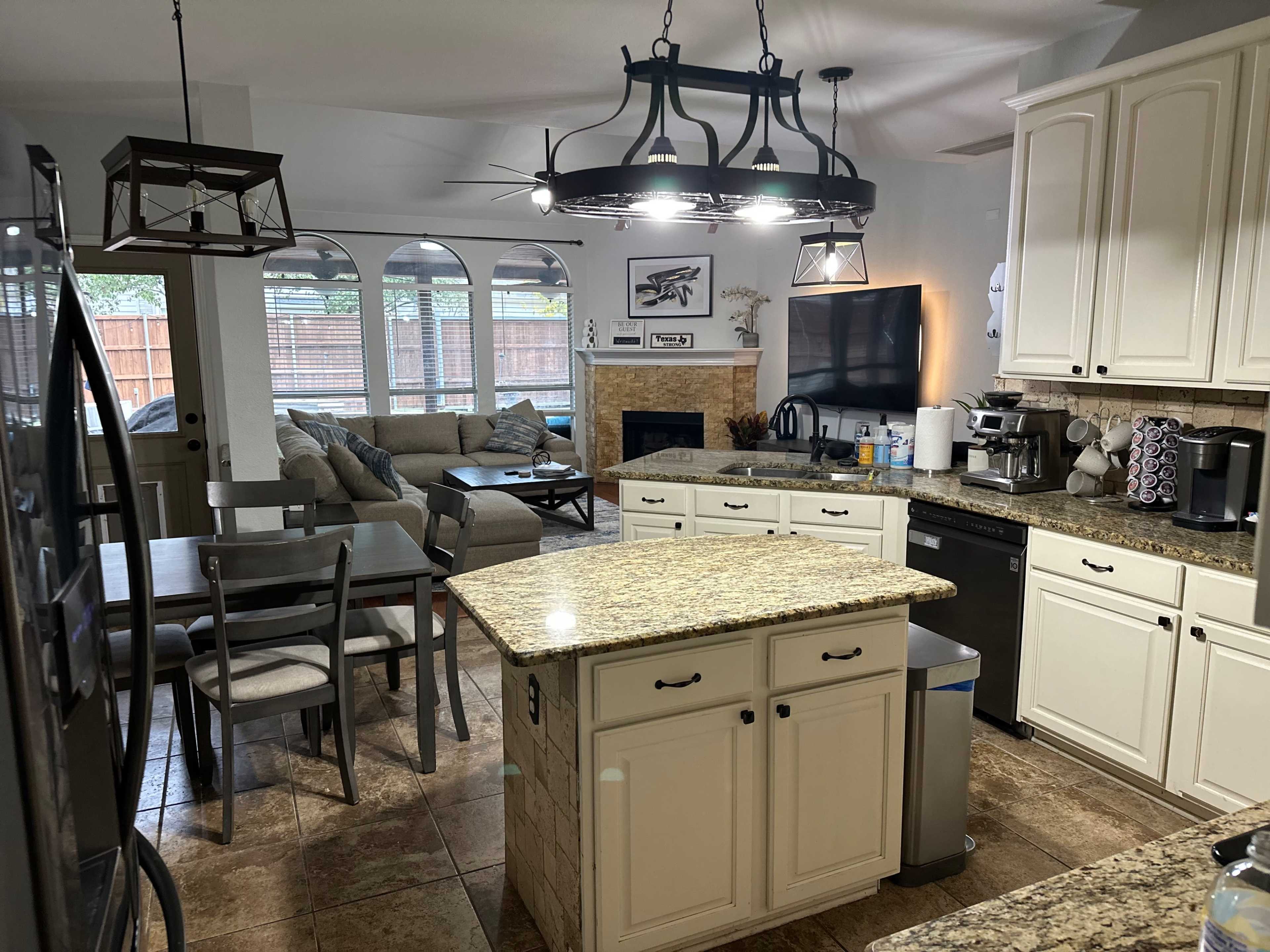 An open-concept kitchen and living area featuring a granite island, a dining table, and a comfortable seating arrangement near a fireplace.