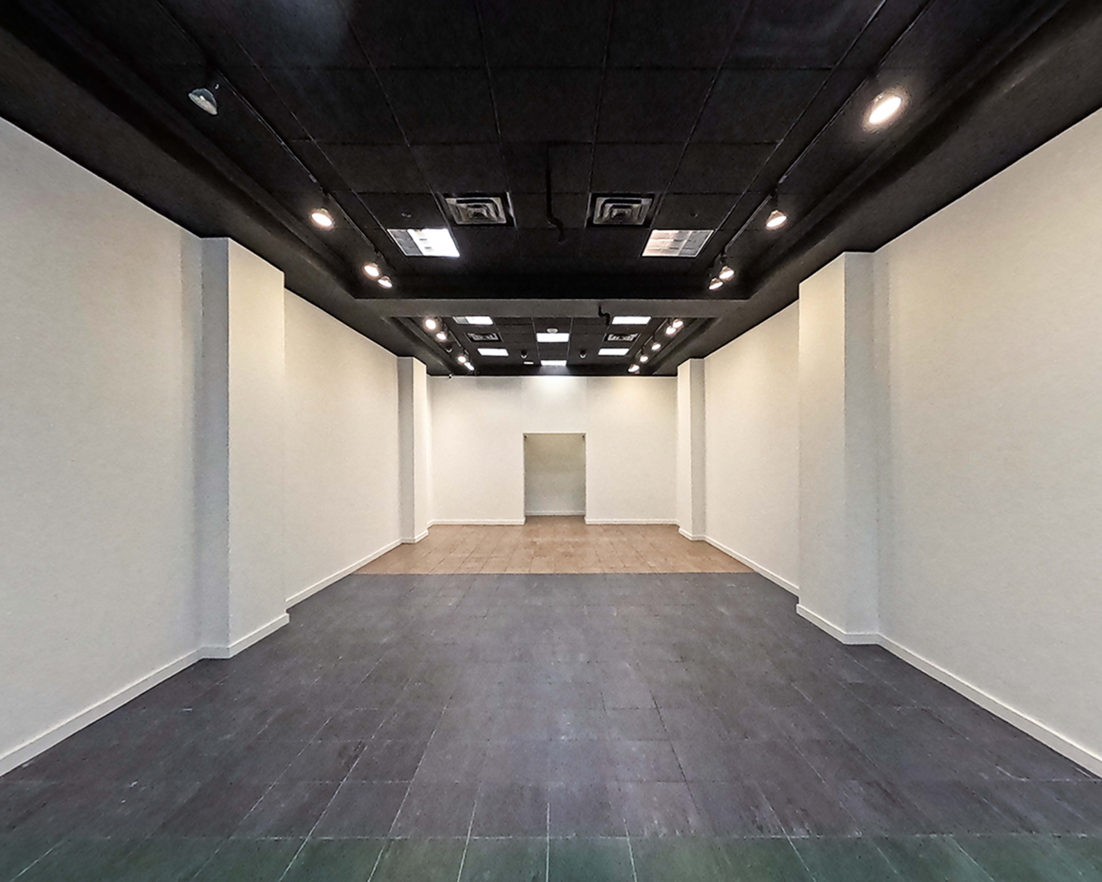 The image shows an empty room with a tiled floor and plain white walls, featuring a doorway at the far end.