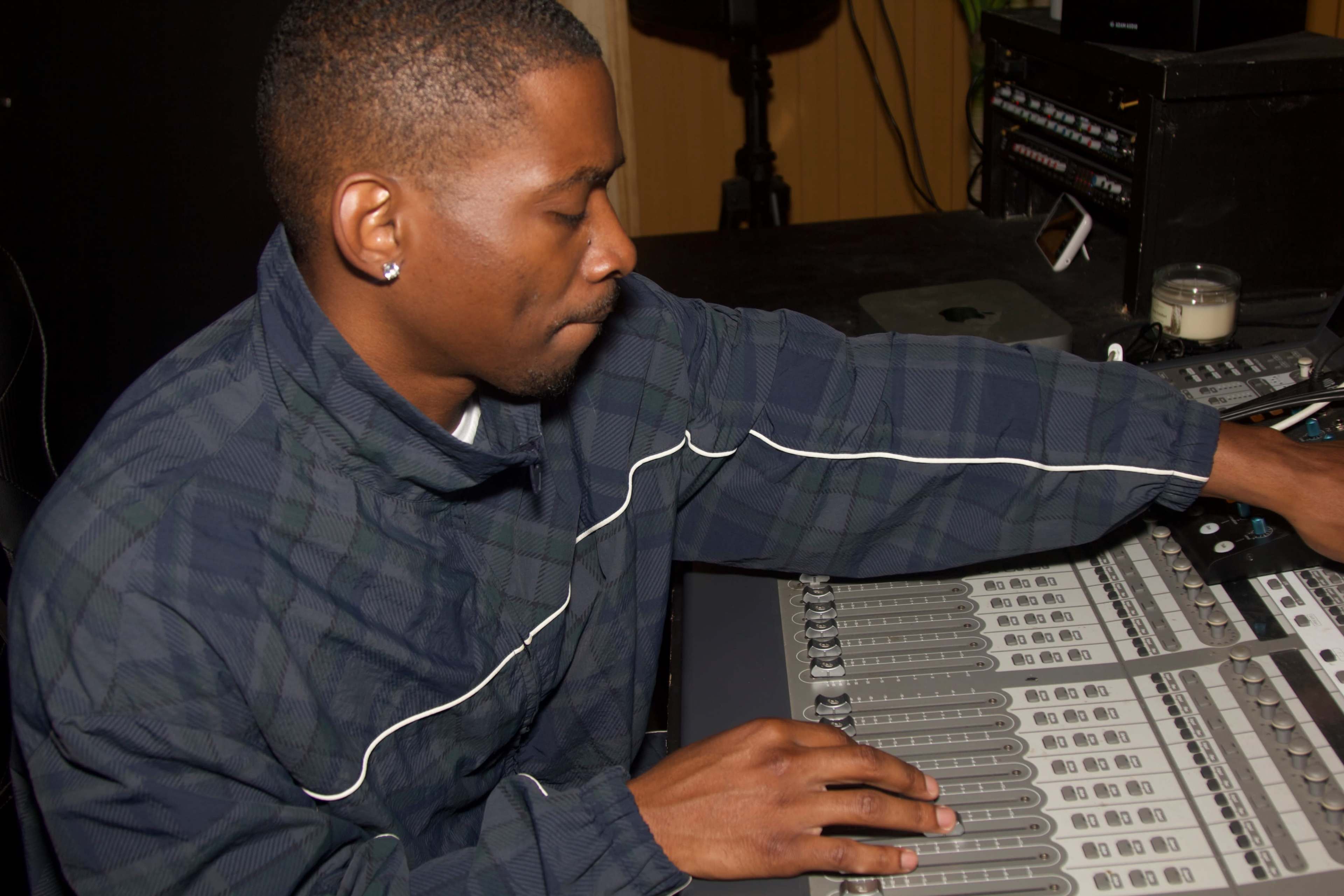 A man operates a sound mixing board in a recording studio.