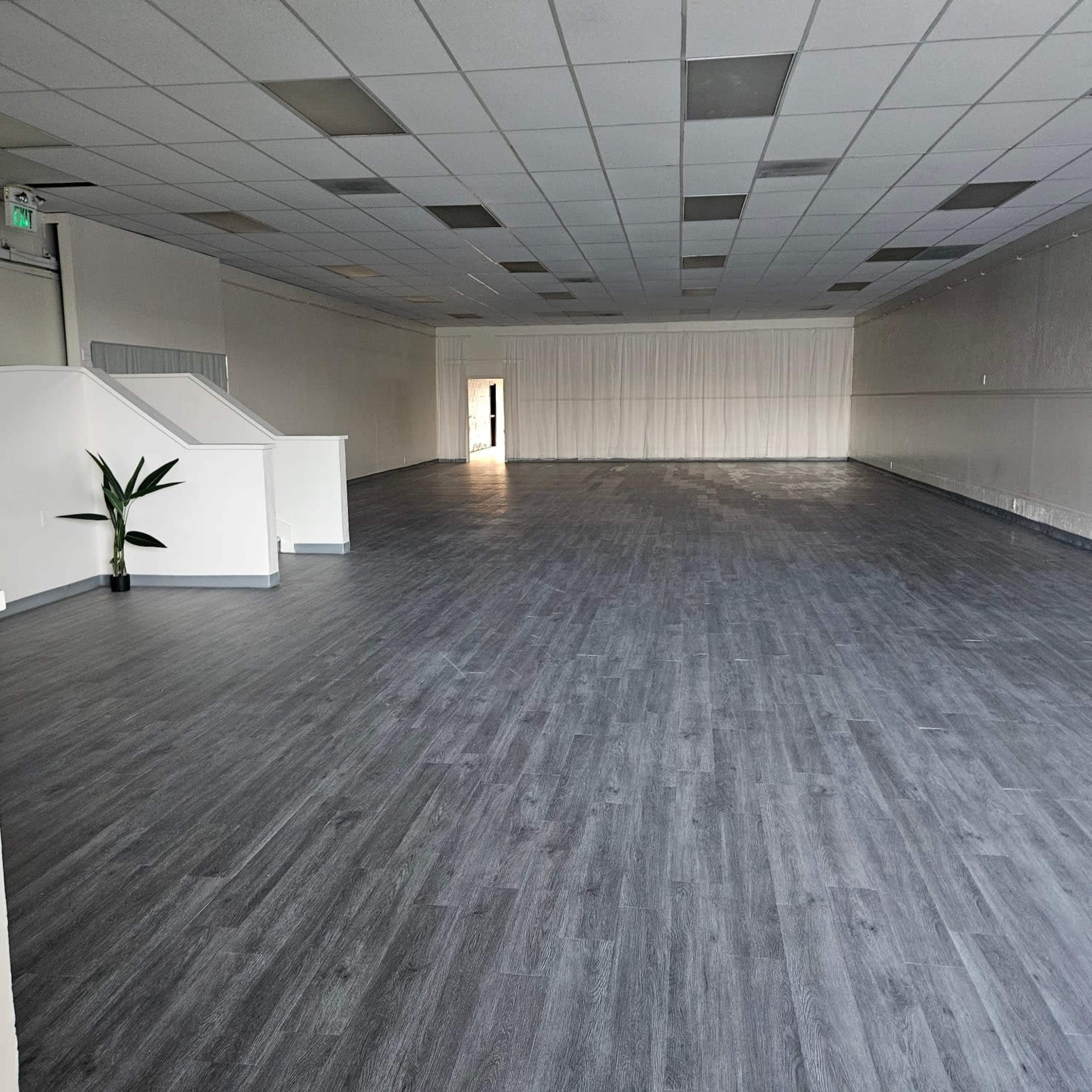 A spacious, empty room with gray wooden flooring and minimal decor.