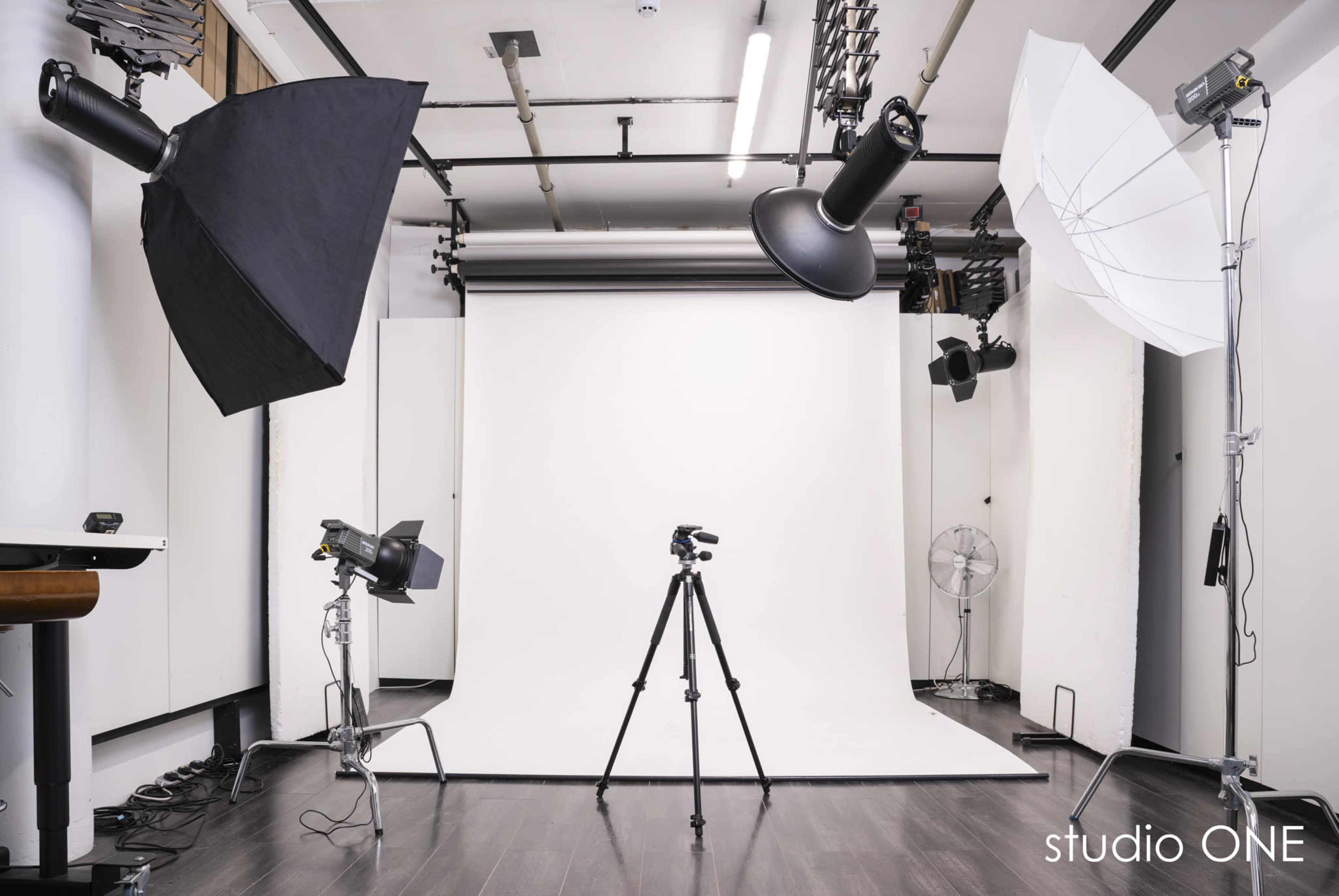 A photography studio is set up with various lighting equipment and a white backdrop.