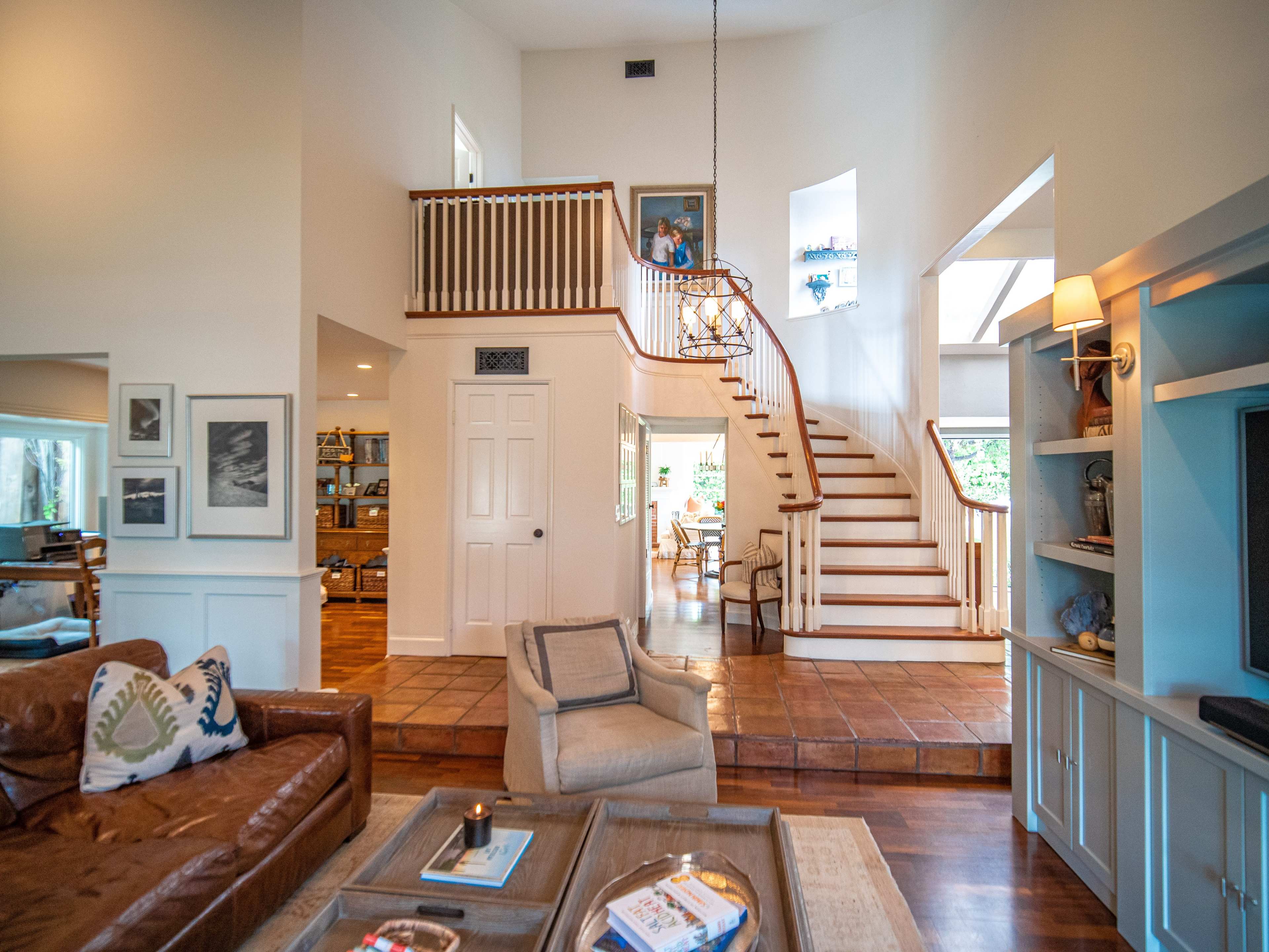 A spacious living room with a staircase leading to an upper level, featuring a large sectional sofa, a coffee table, and an adjacent dining area.