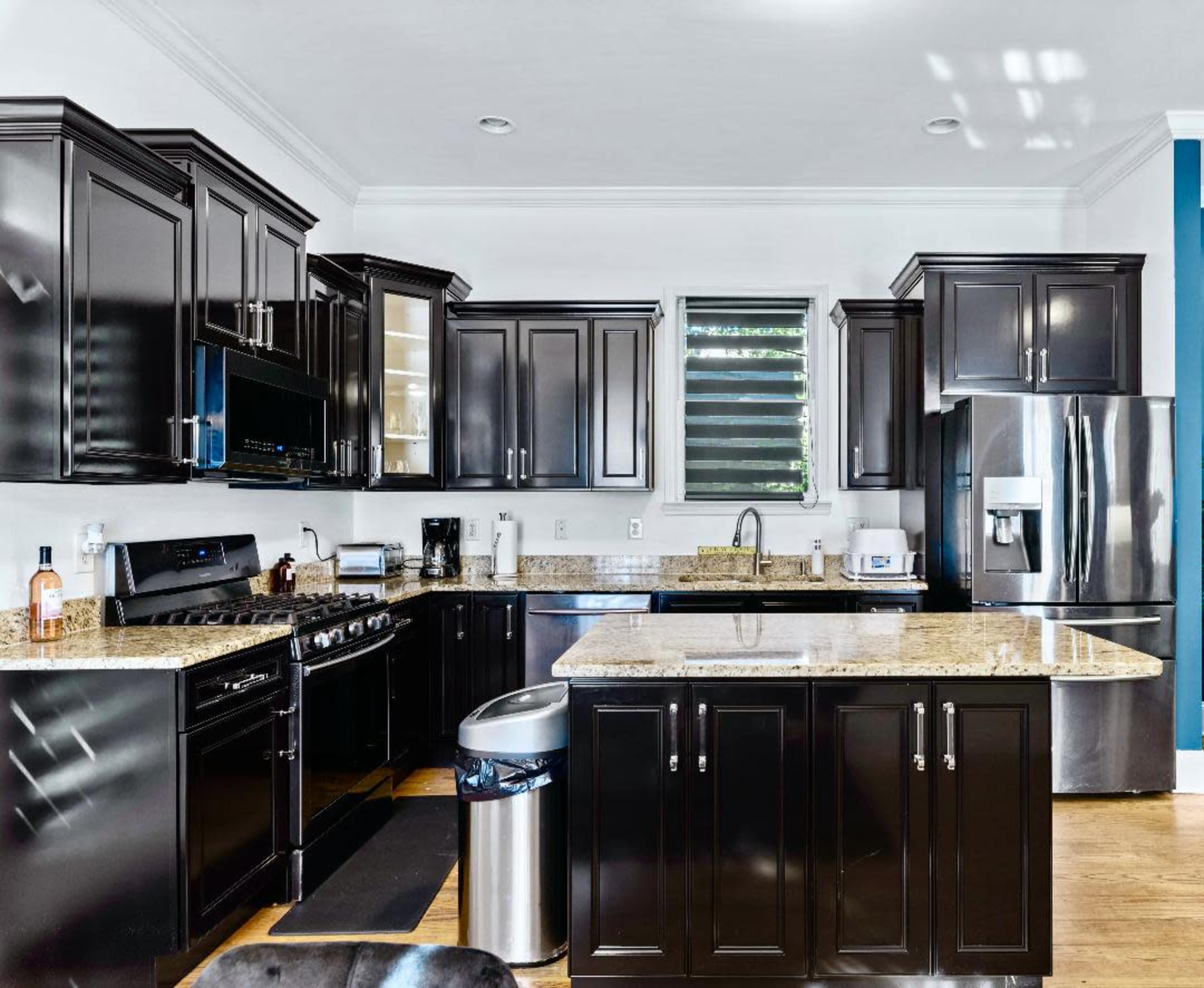 The kitchen features dark cabinetry, a stainless steel refrigerator, and a granite countertop with a central island.