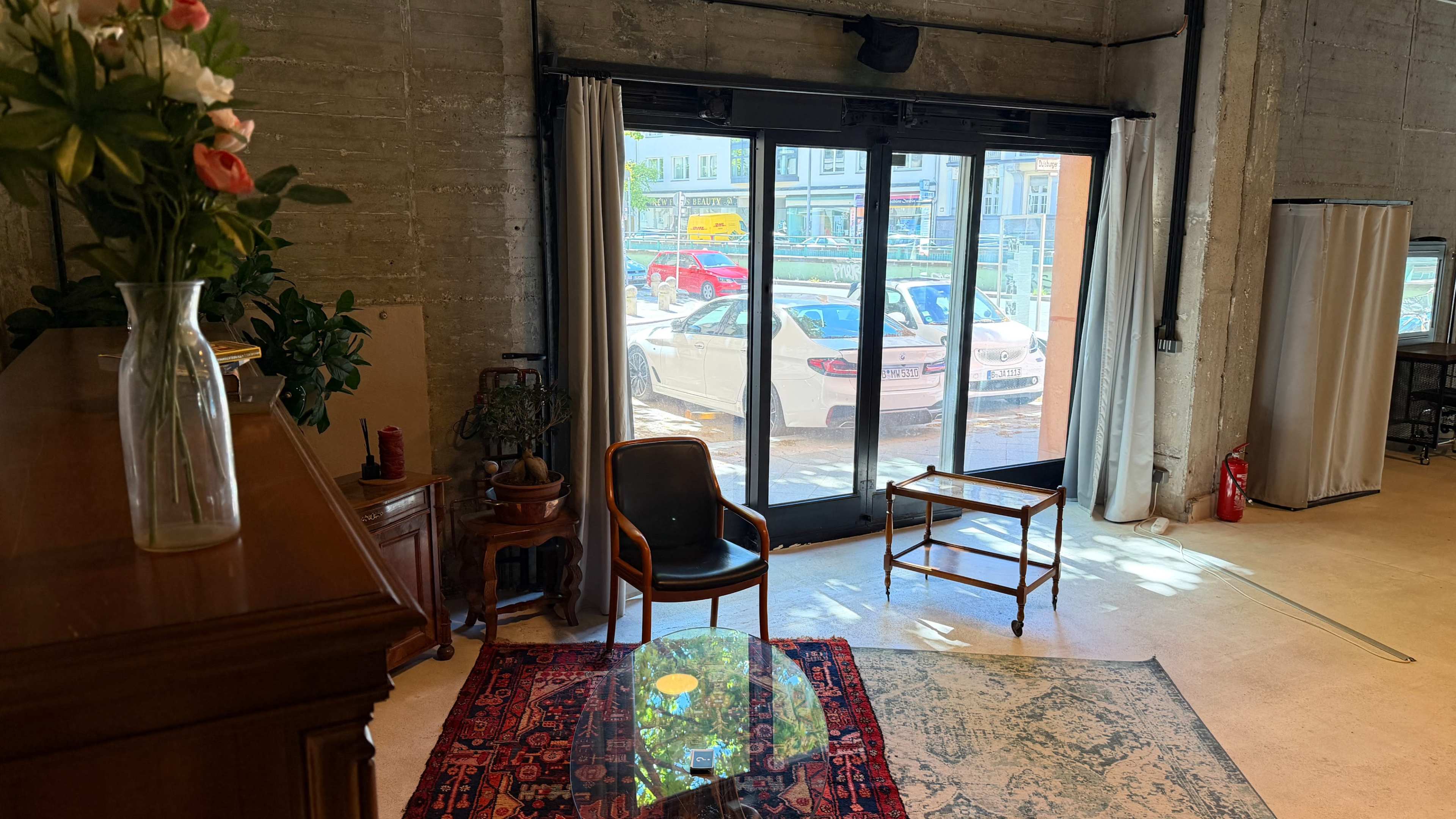 A chair and a small table are positioned on a patterned rug in a room with large glass doors leading to an outdoor view.