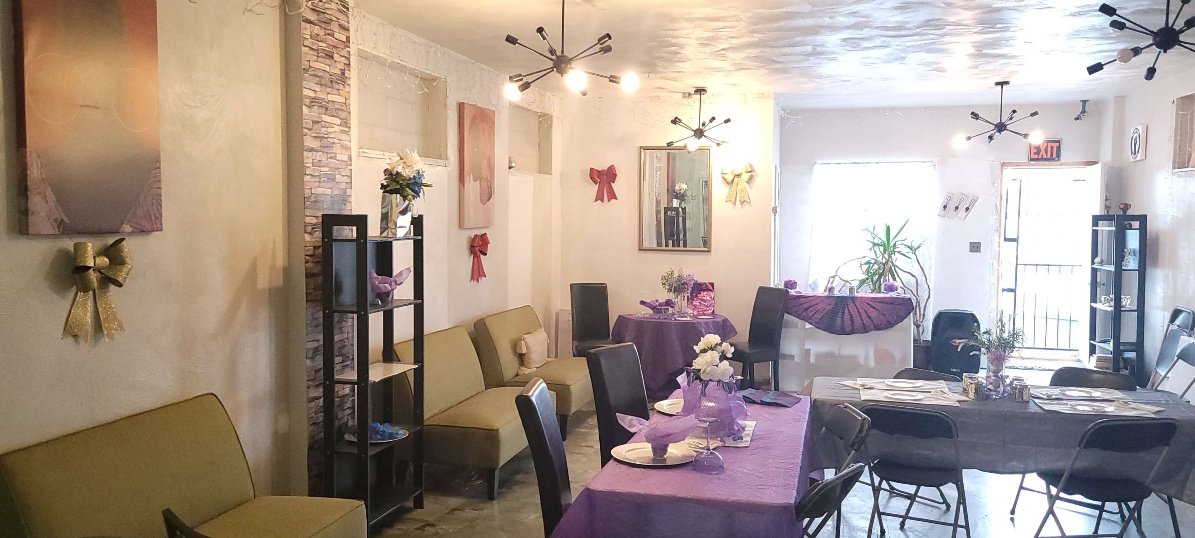 A well-decorated dining area features several tables with purple tablecloths, an assortment of seating, and decorative elements on the walls.