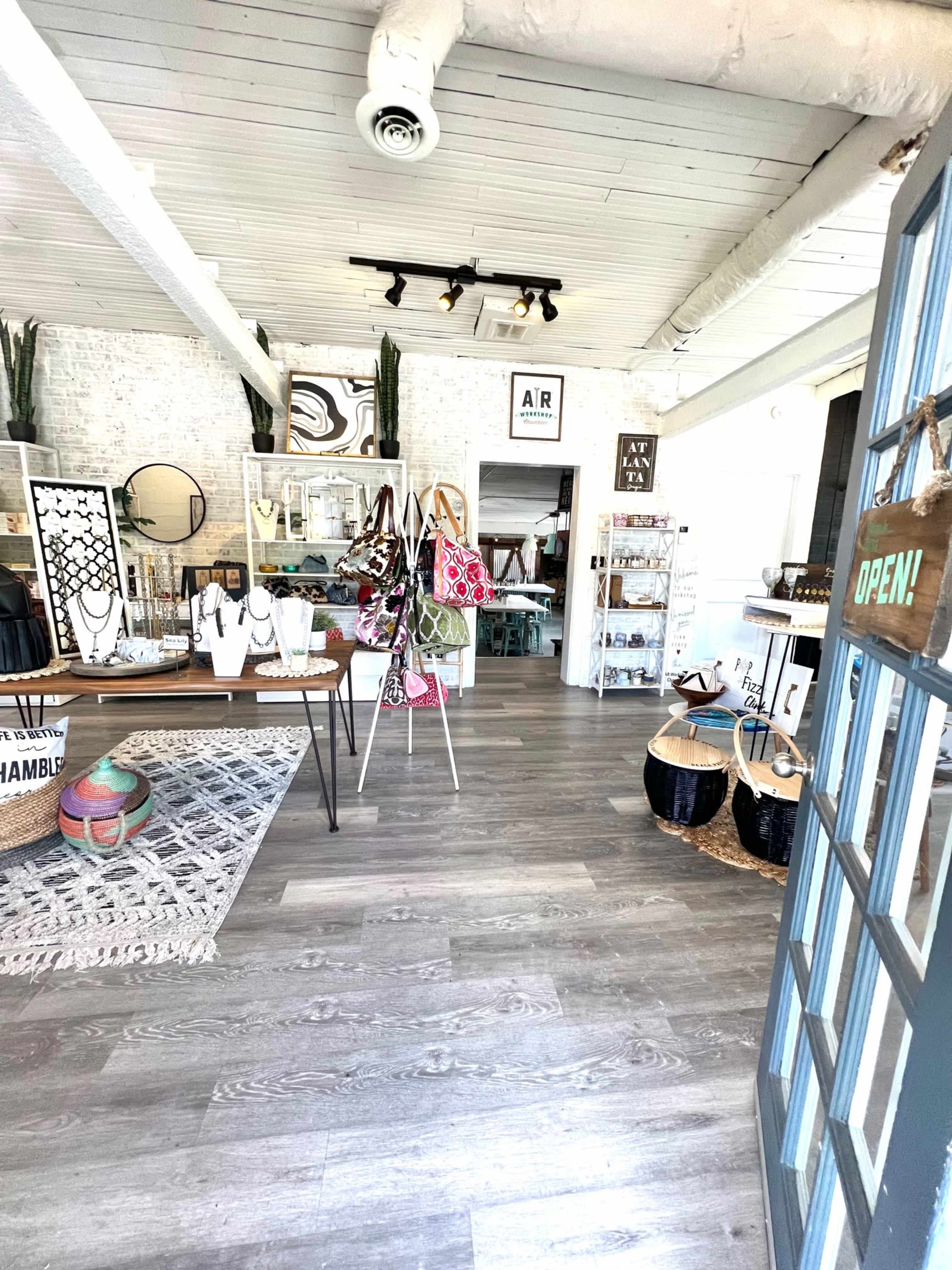 The interior of a boutique with displays of jewelry, home decor, and accessories, featuring wooden furniture and a bright atmosphere.