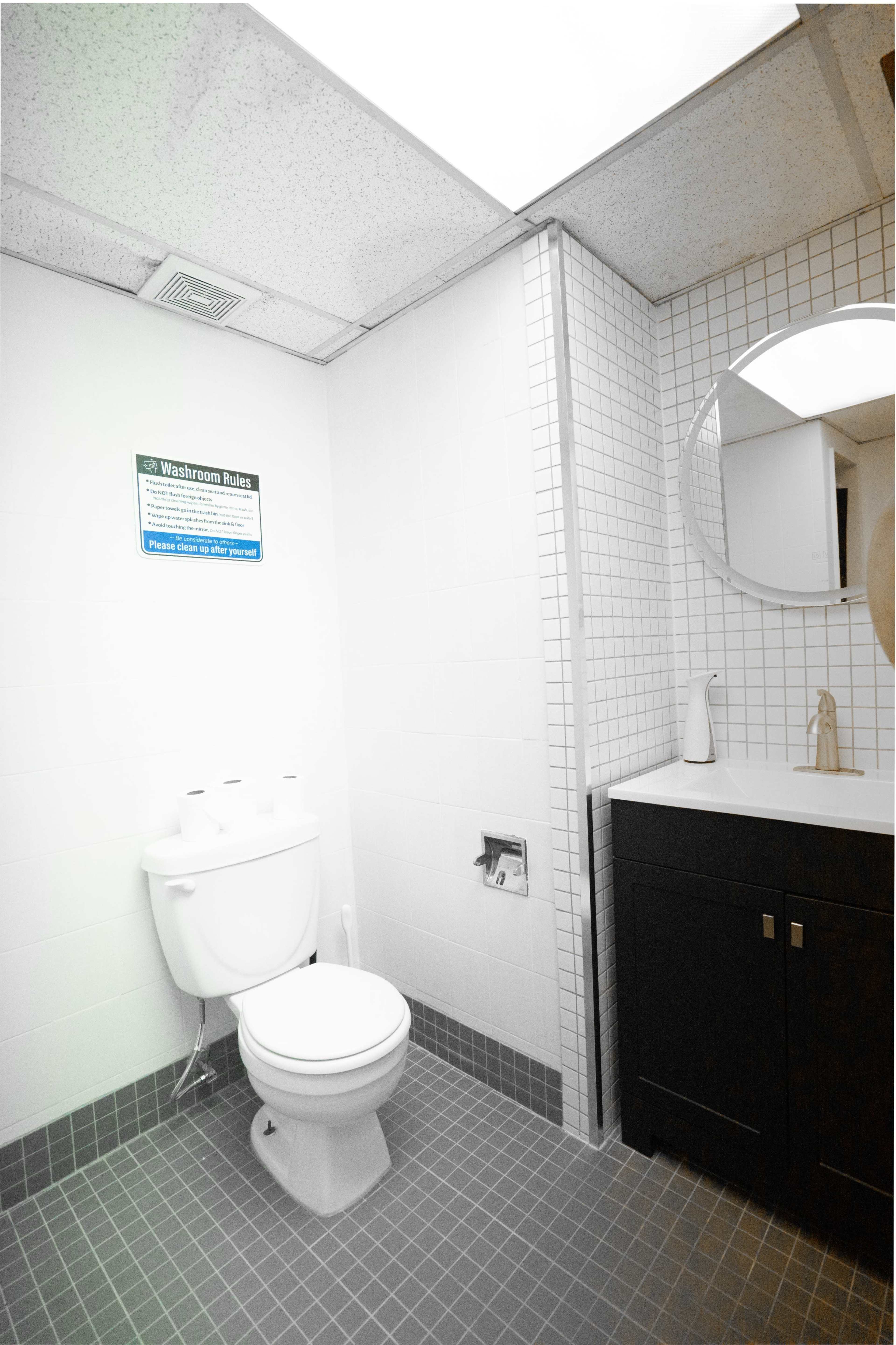 The image shows a restroom featuring a toilet and a small sink with a mirror on the wall.