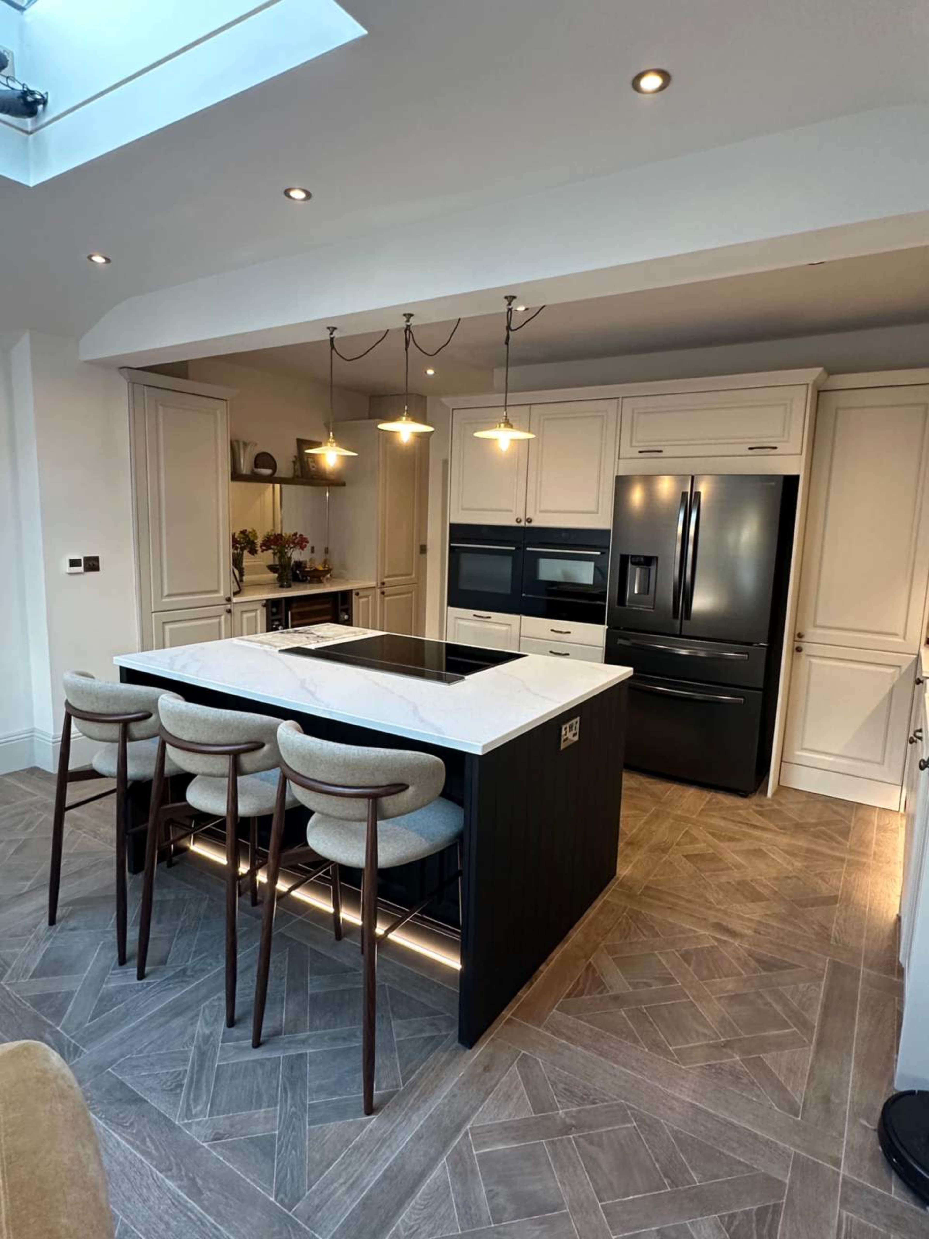 The image shows a modern kitchen featuring an island with seating, sleek cabinetry, and black appliances.