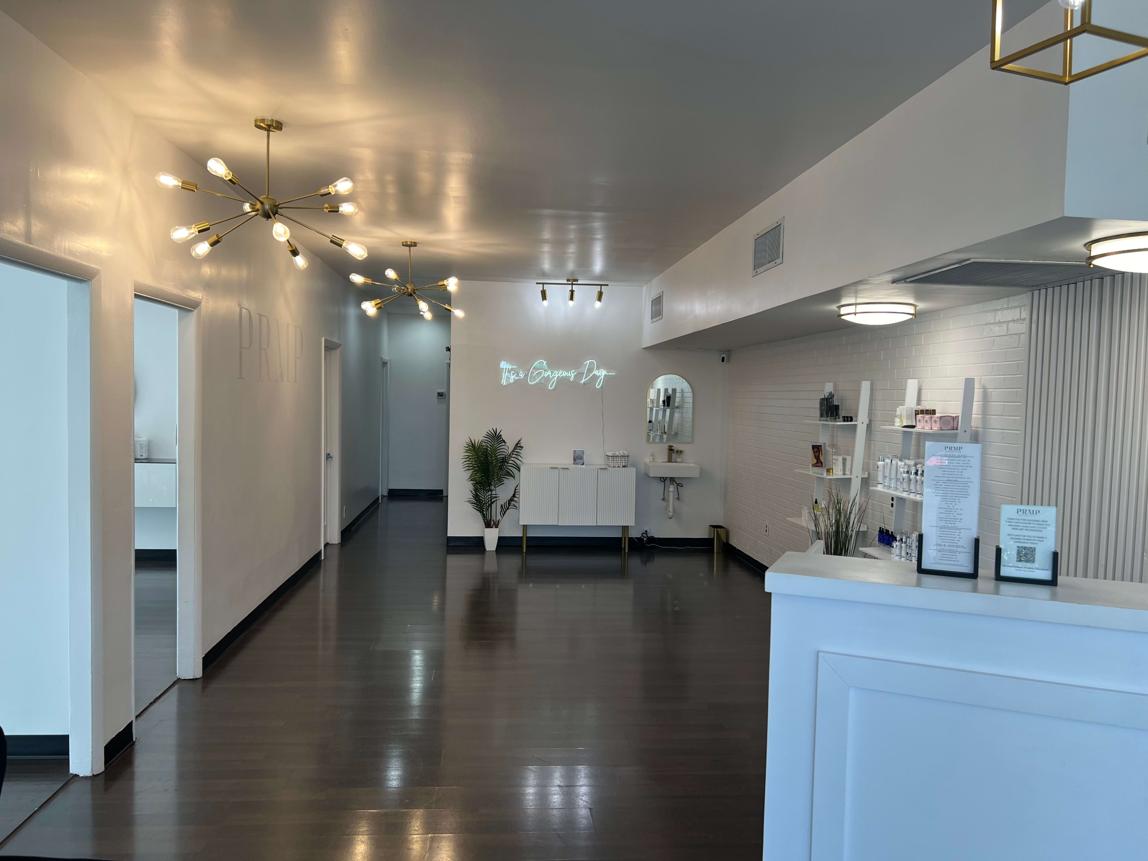 A modern, minimalist reception area with a sleek design, featuring white walls, stylish lighting fixtures, and product displays.