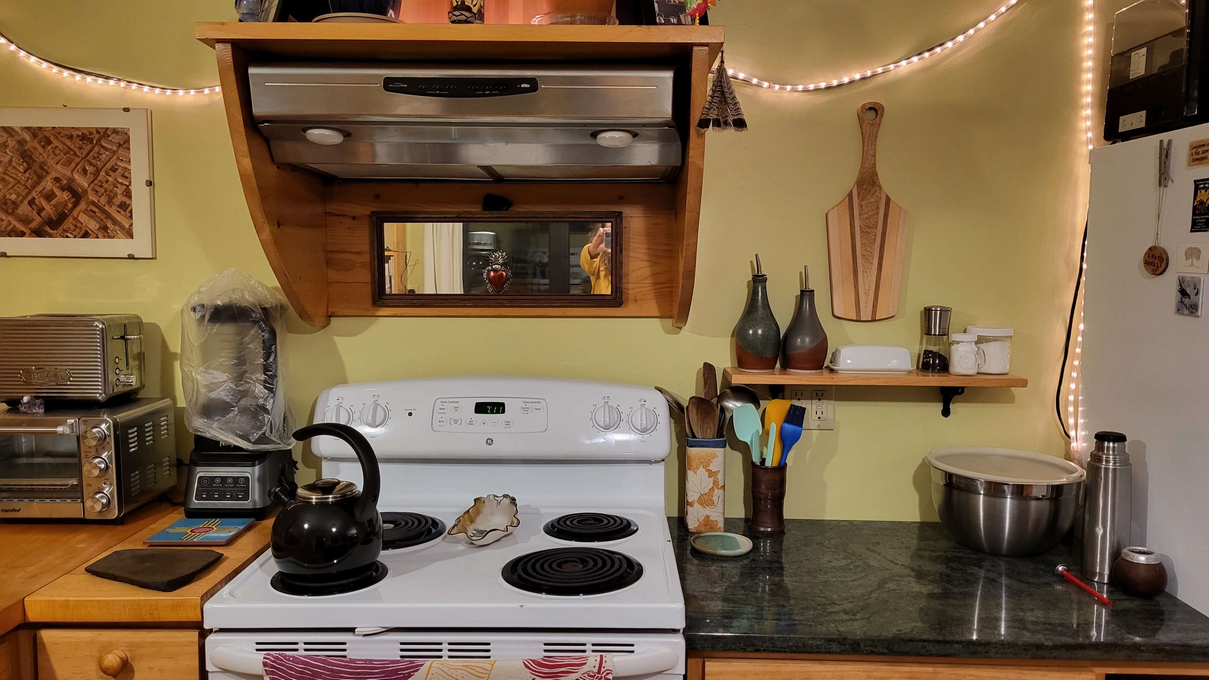 A kitchen with a stove, a kettle on the burner, and various kitchen utensils and appliances on the counters.