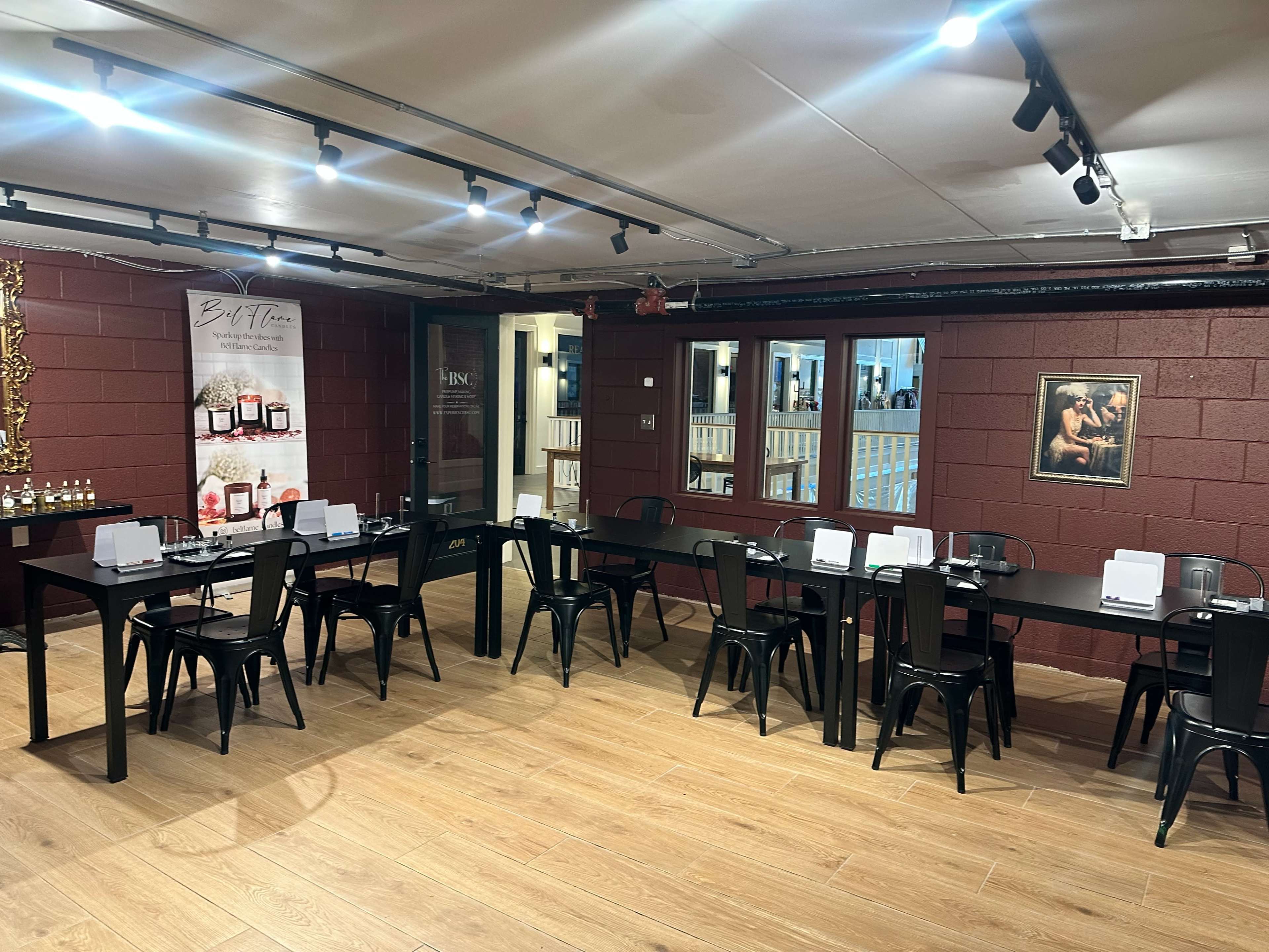 The image shows a spacious room with several long black tables arranged in two parallel lines, each set for a gathering with white papers and chairs.