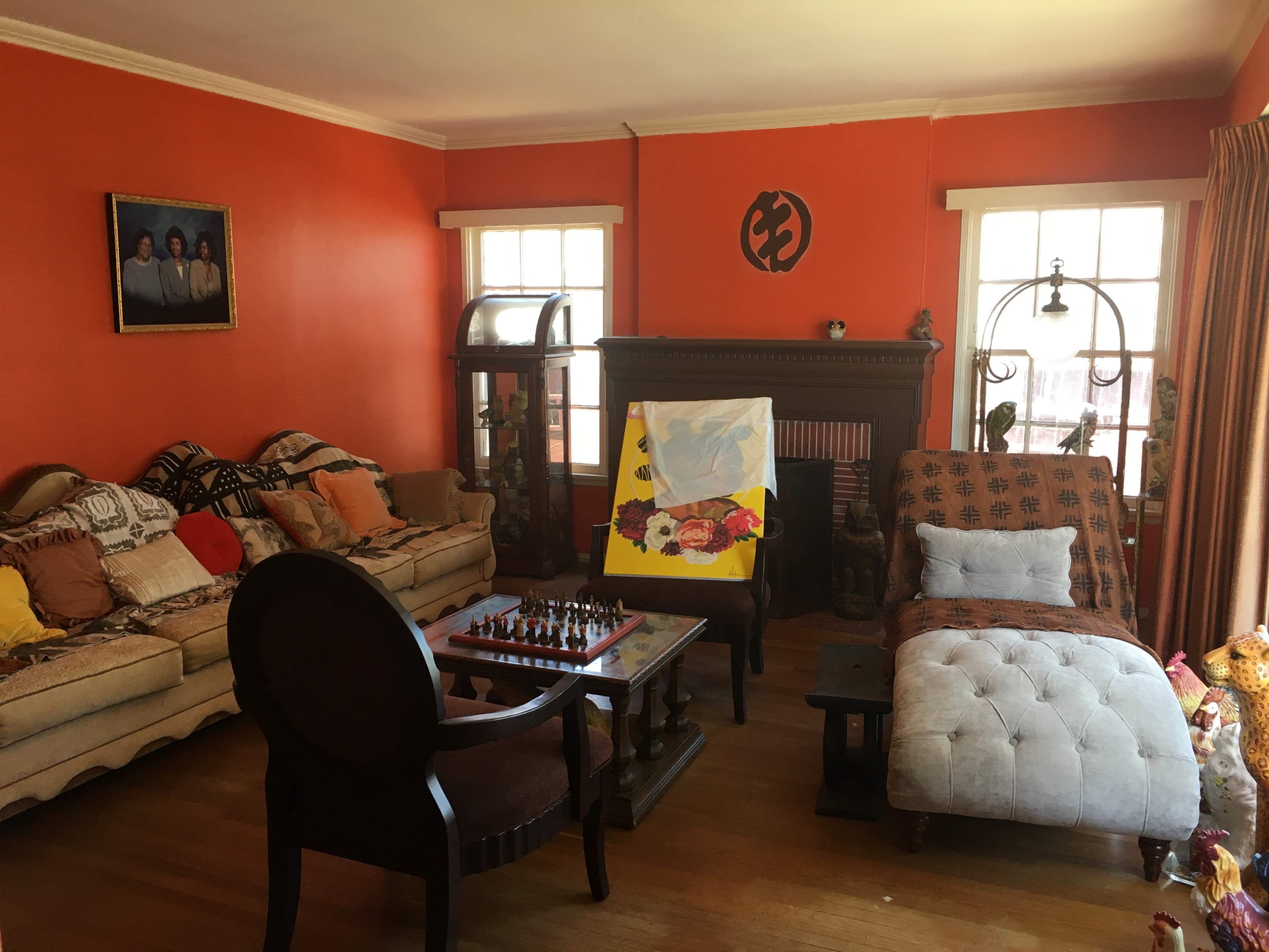 The room features a chess set on a table, a chaise lounge, and two sofas against orange-colored walls.