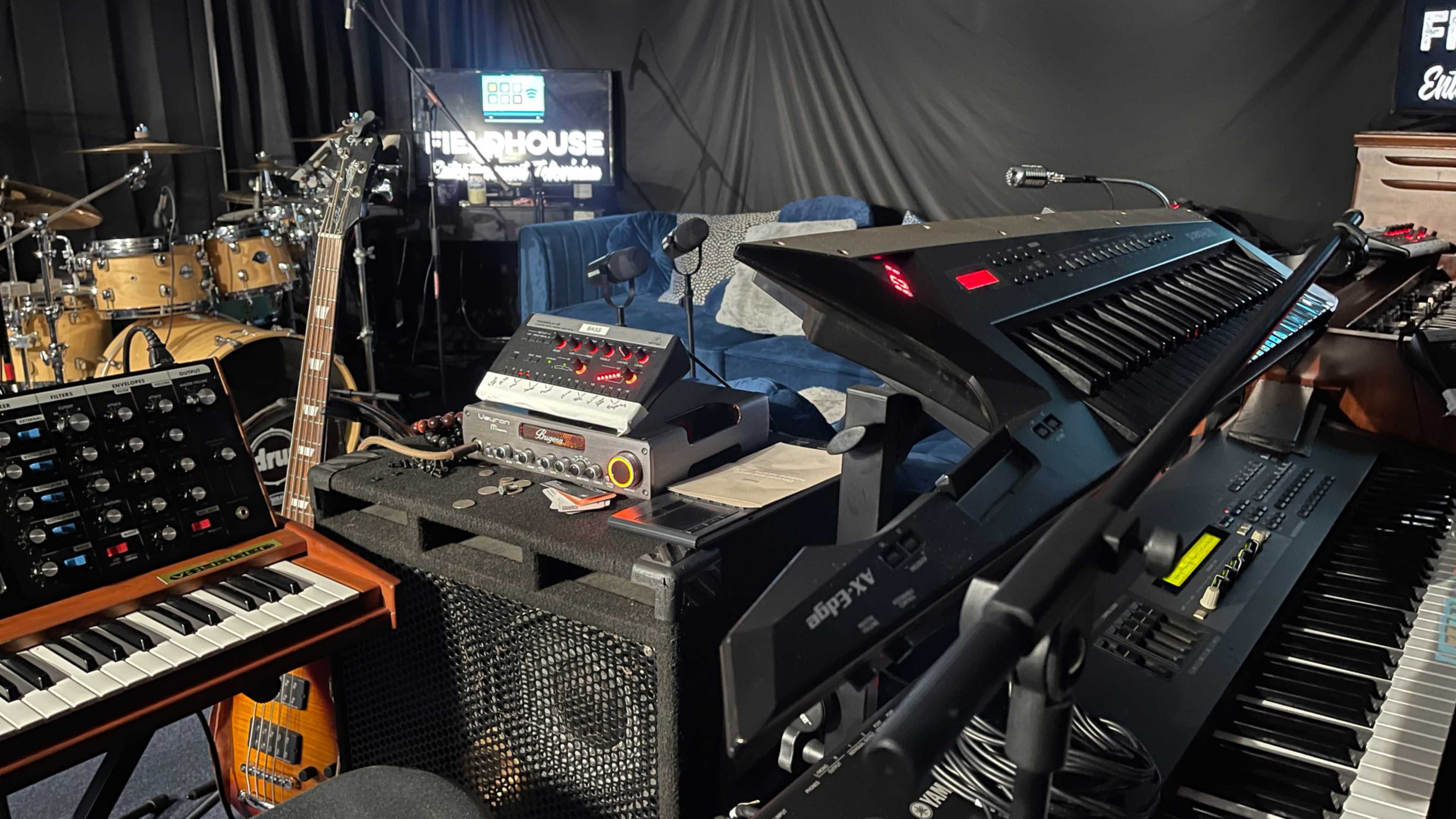 A music setup featuring various instruments, including a keyboard, a guitar, and audio equipment, in a studio environment.