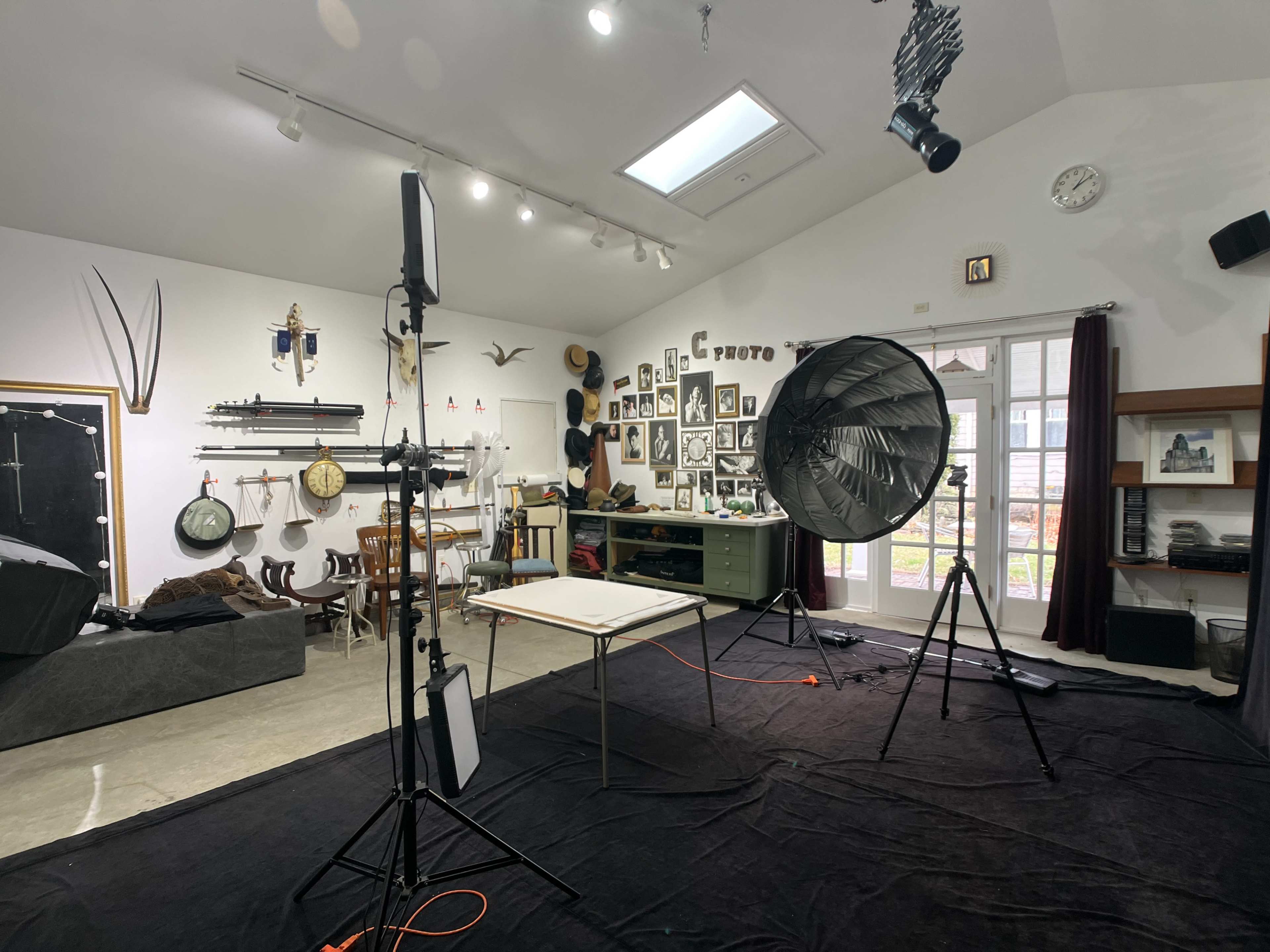 A photography studio equipped with lighting equipment, a backdrop, and various framed photographs displayed on the walls.