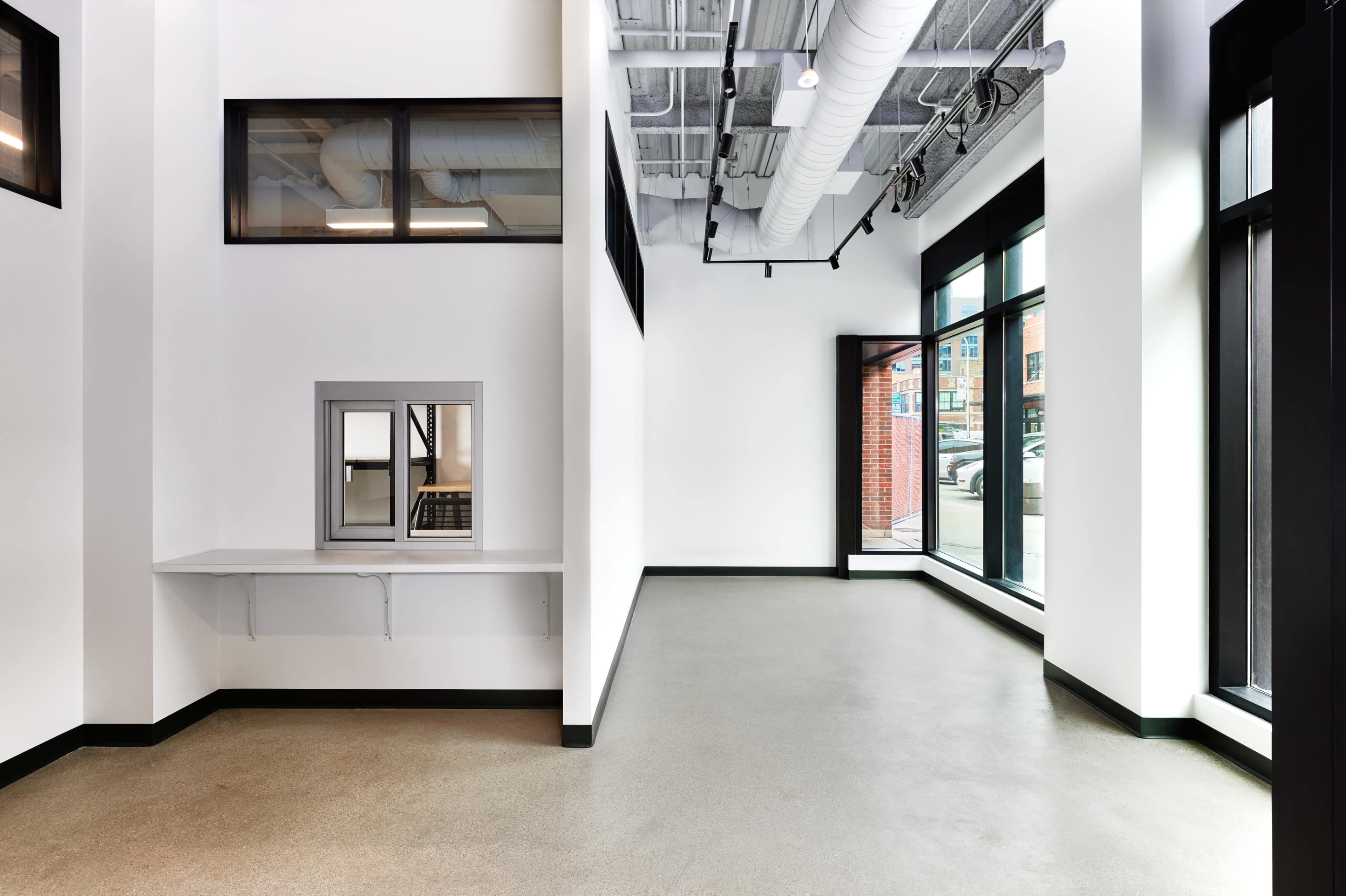 An empty, modern interior space with large windows and minimal furnishings.