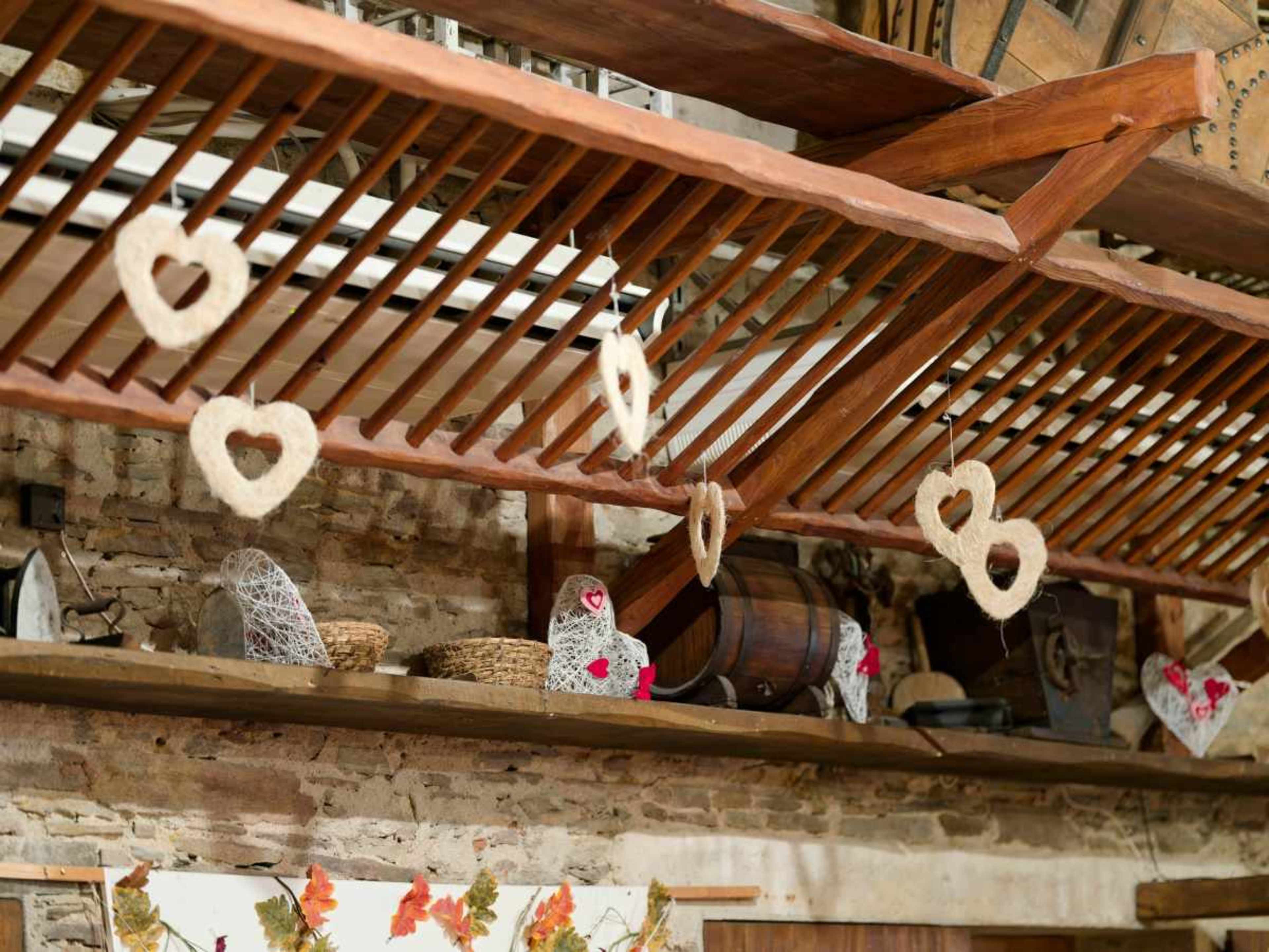 The image shows a wooden shelf in a rustic setting, adorned with heart-shaped decorations hanging from overhead beams.