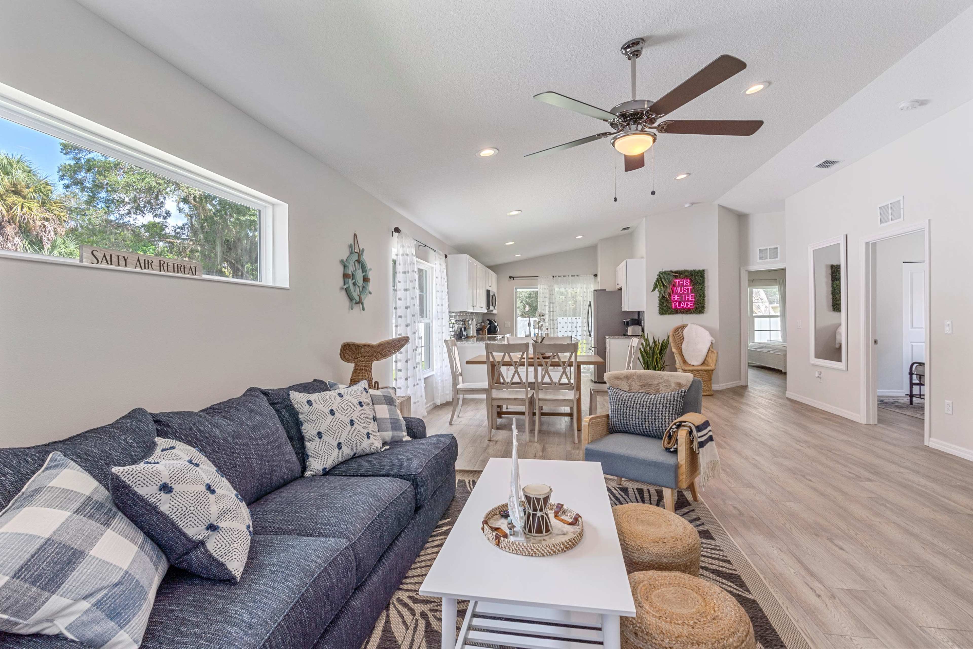 A modern living room with a sectional sofa, a coffee table, and a view of an adjoining kitchen and dining area.