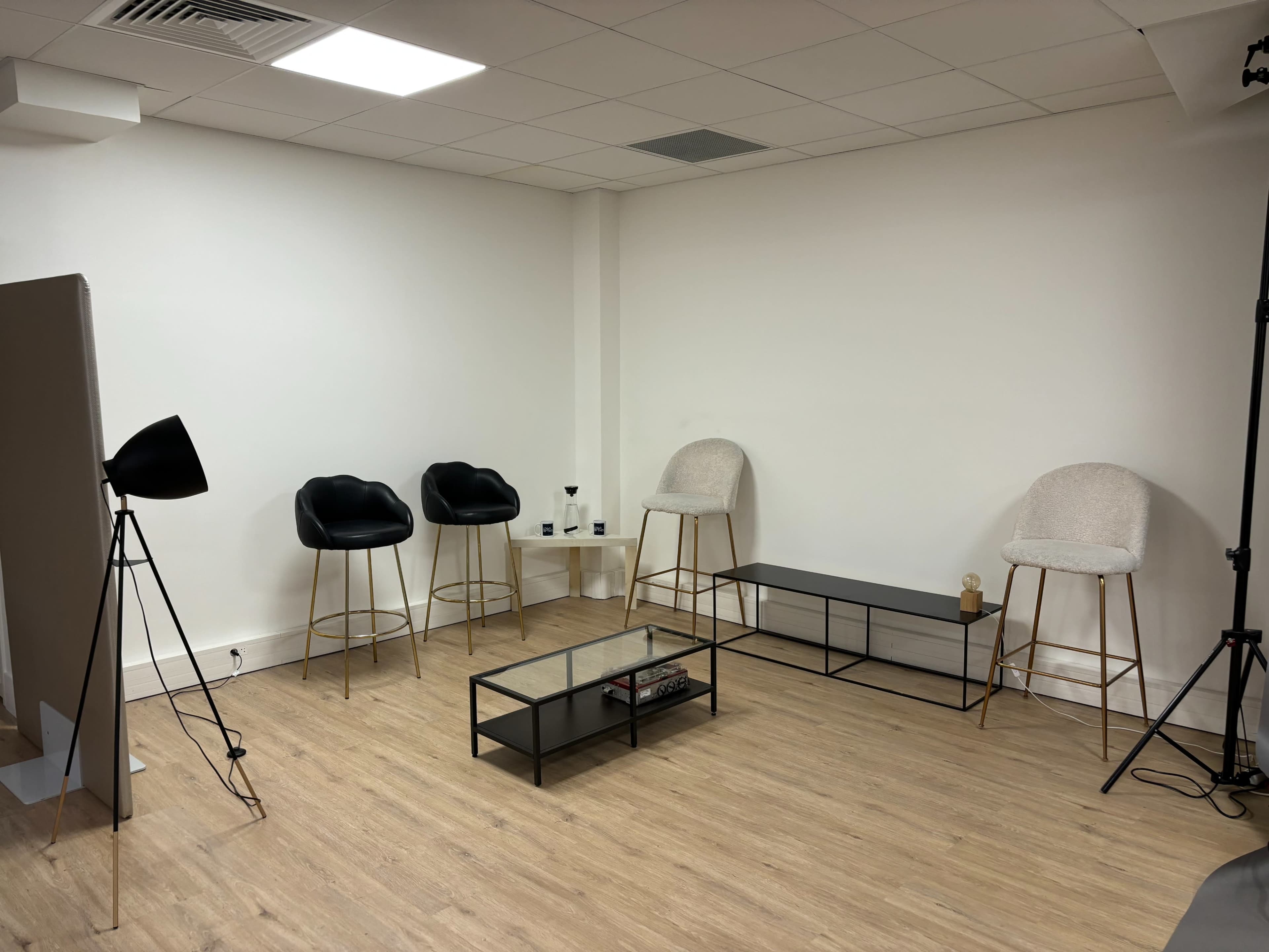 A minimalist room with two black bar stools, two light-colored stools, a rectangular coffee table, and a floor lamp.