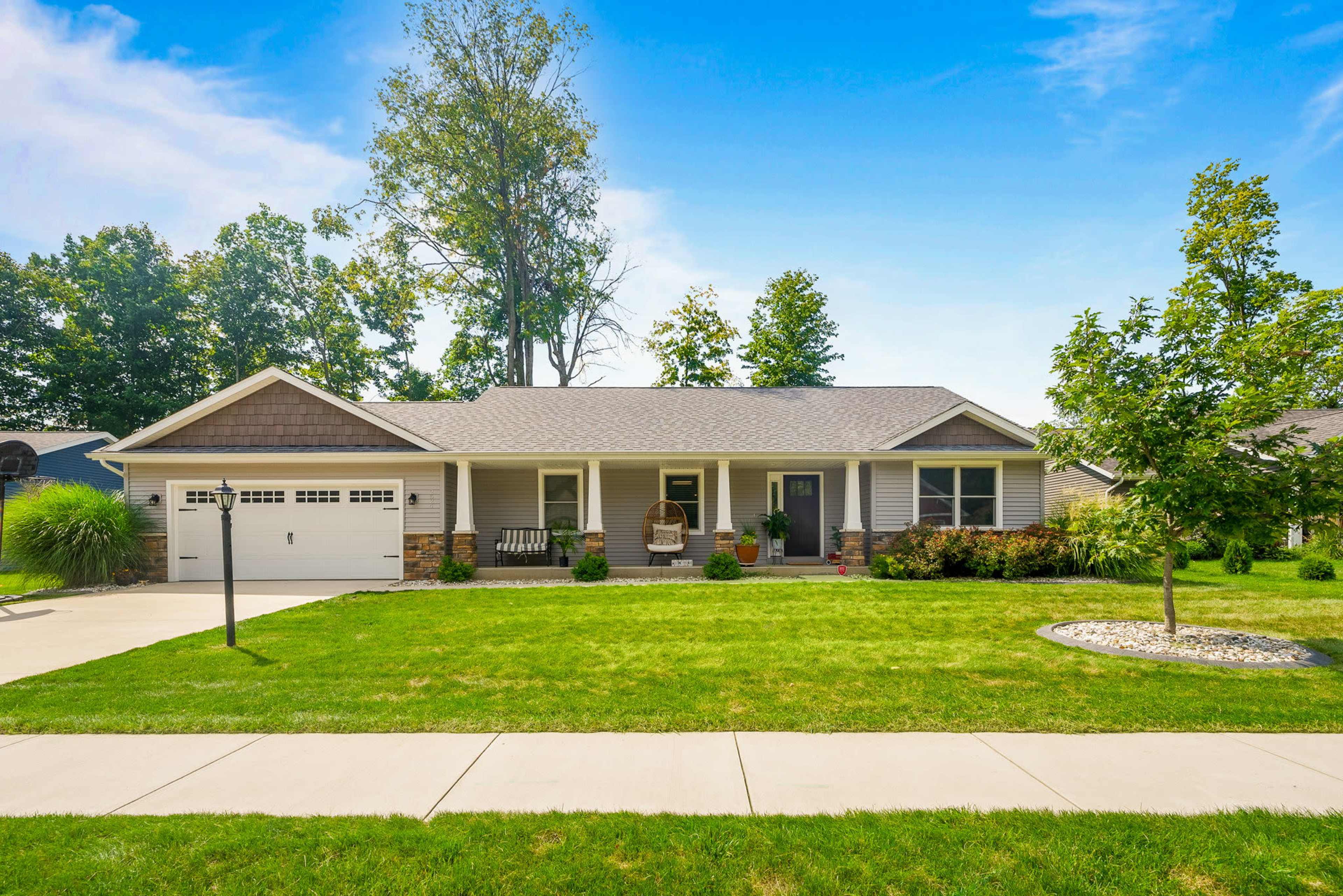 A single-story house with a front porch, surrounded by a well-maintained lawn and a sidewalk.