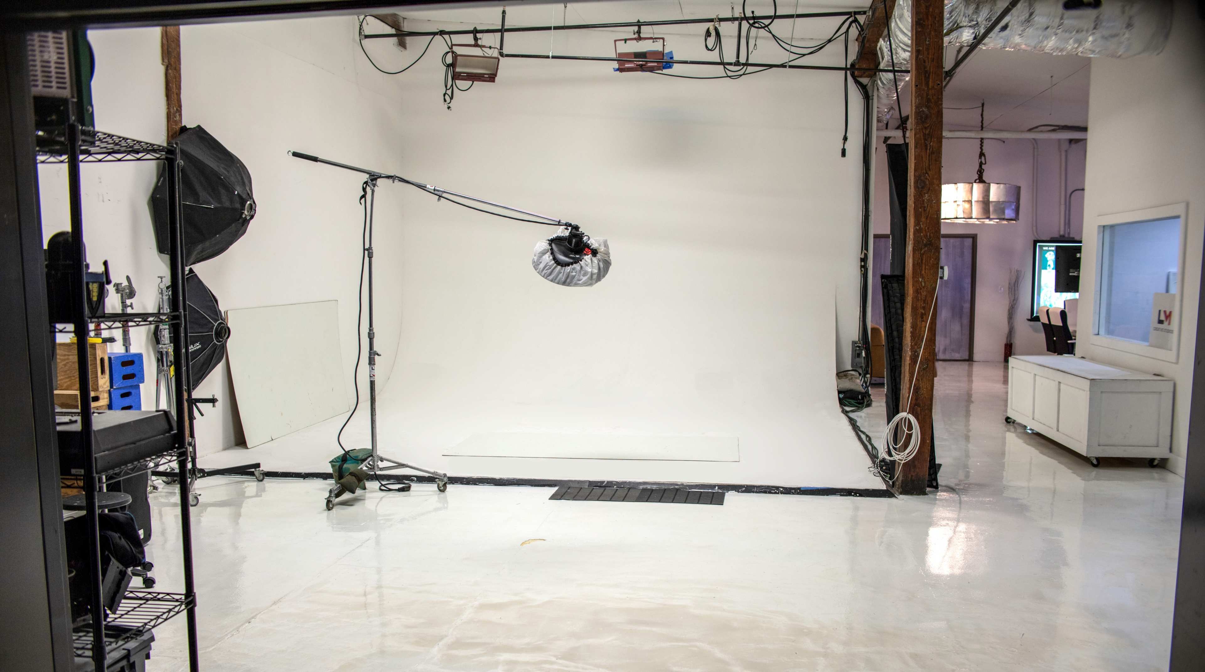 A photography studio with a white backdrop, lighting equipment, and various props arranged along the sides.
