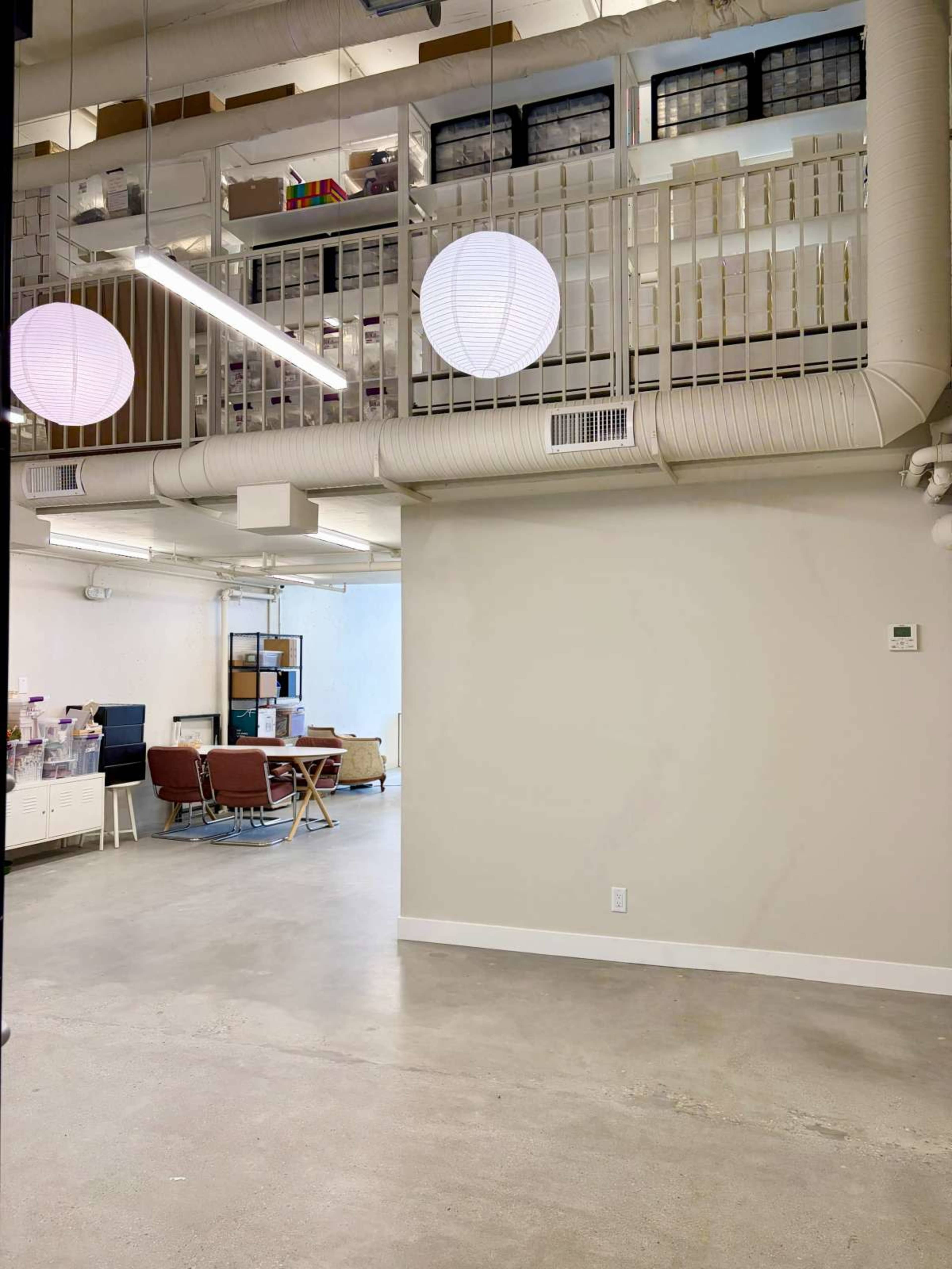 The image shows a modern office space with a lofted area and two hanging round light fixtures.