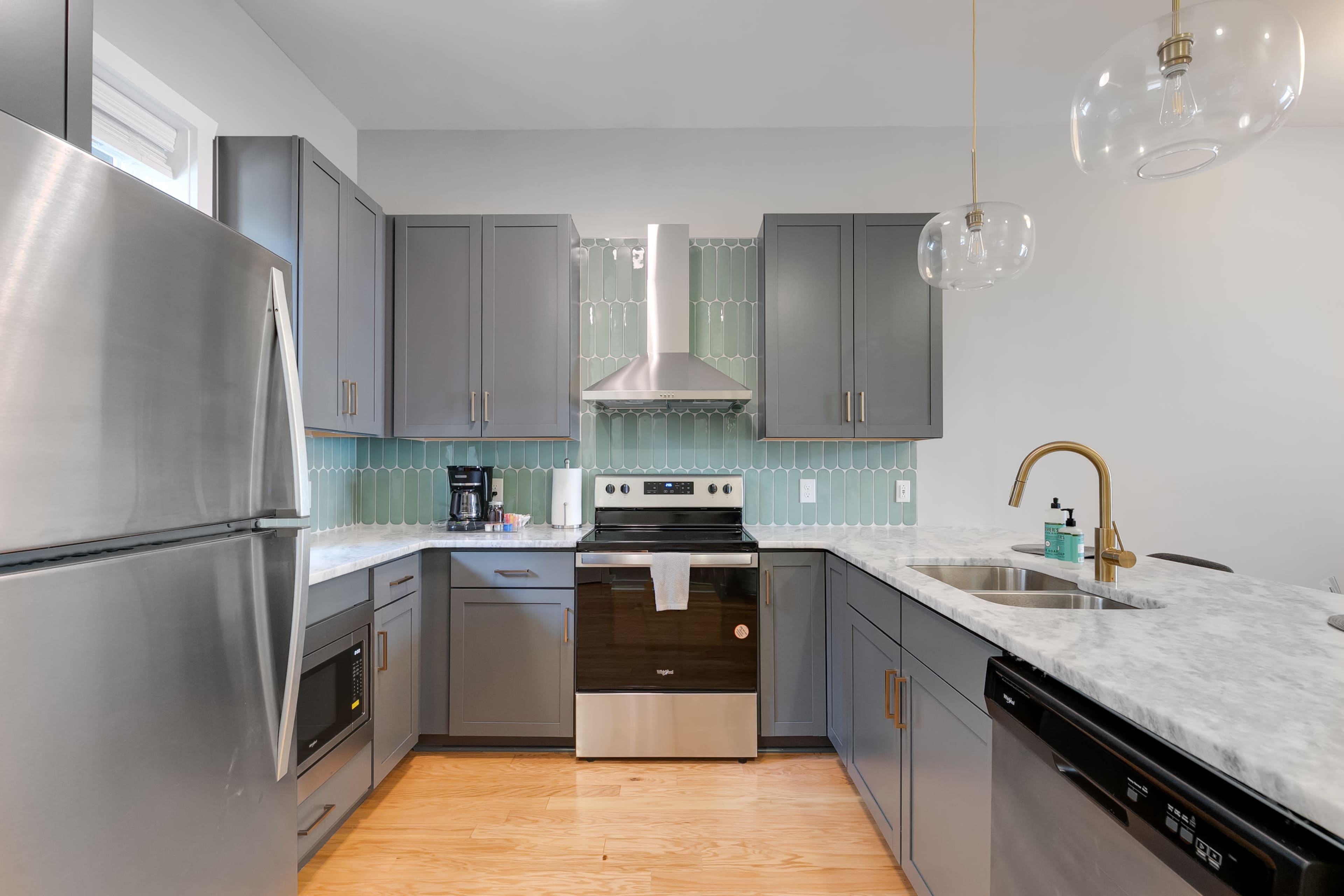The kitchen features stainless steel appliances, gray cabinetry, and a marble countertop with a decorative backsplash.