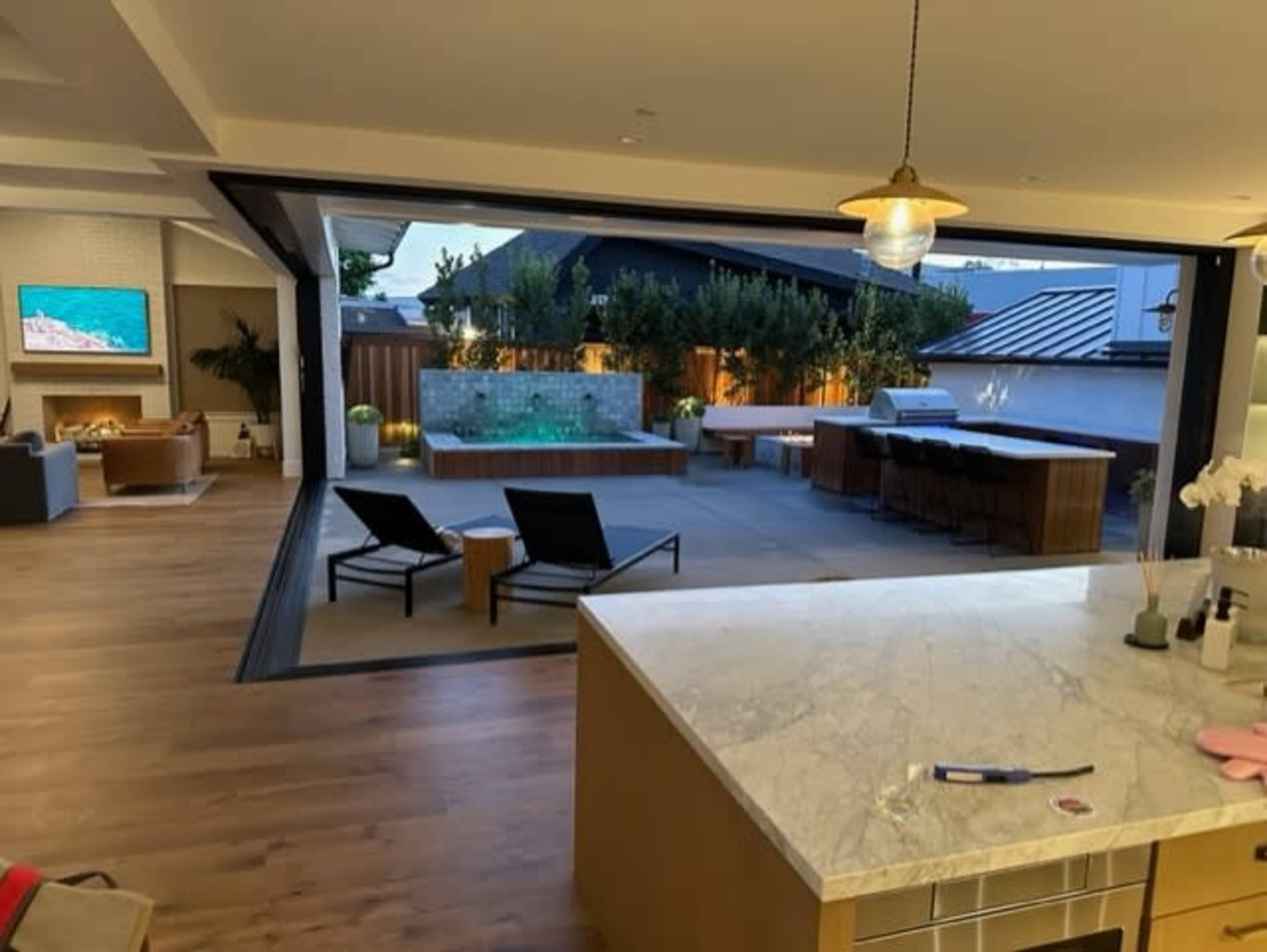 A modern open-concept kitchen offers a view of an outdoor patio with a pool and seating area.