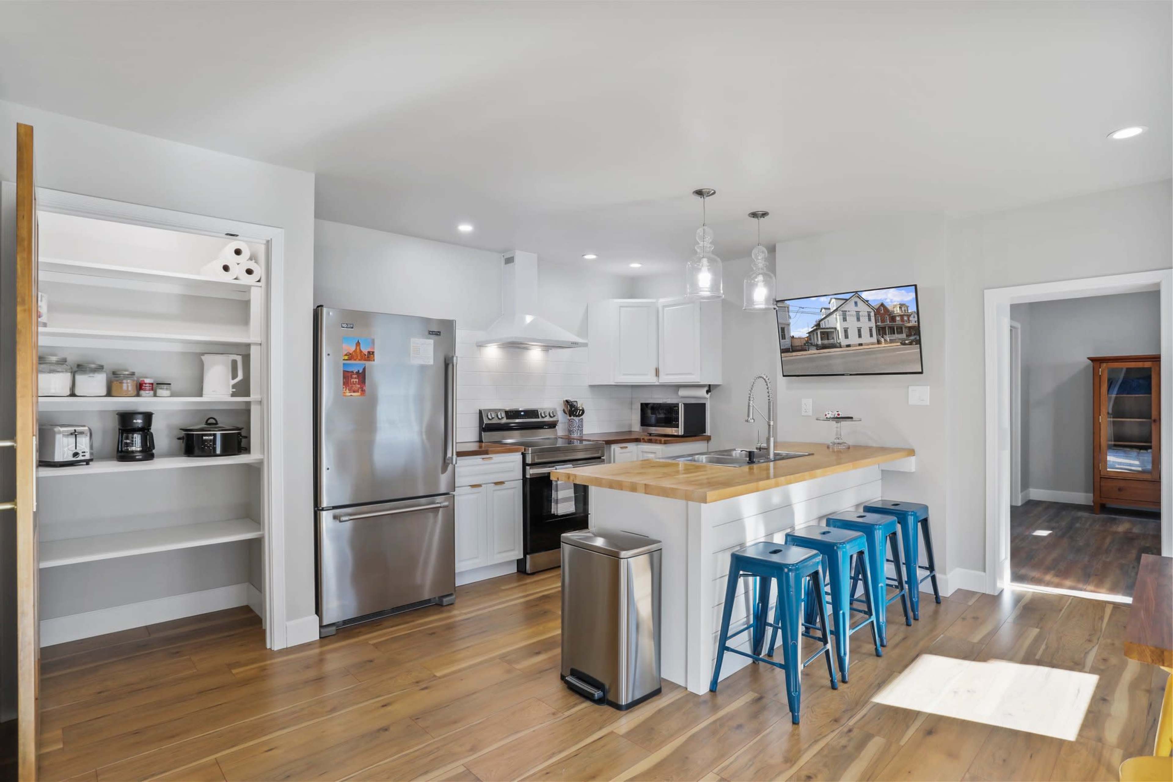 A modern kitchen with a large island, stainless steel appliances, and light wood flooring.