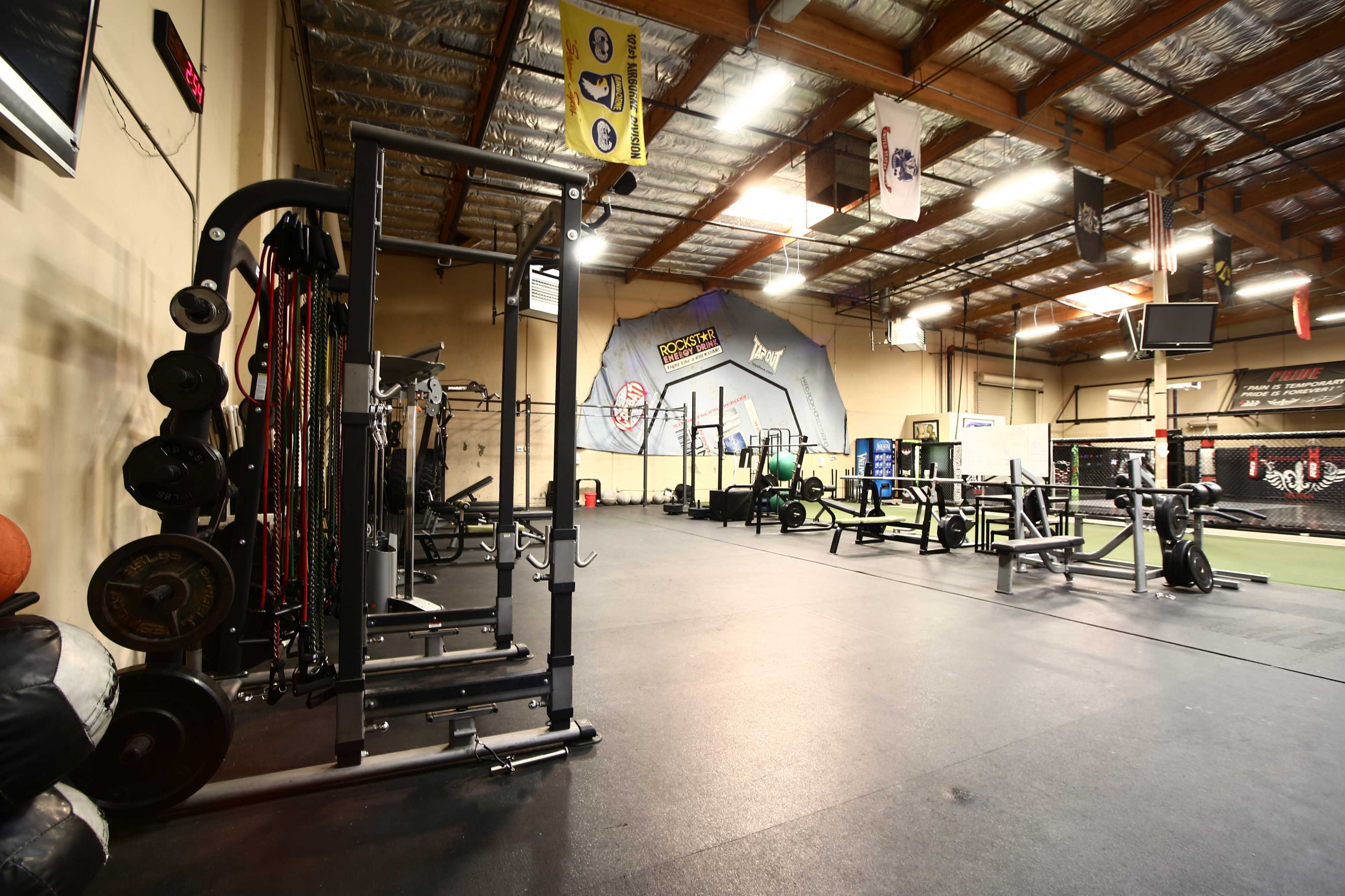 A spacious gym interior with various exercise equipment arranged neatly on a rubber floor.