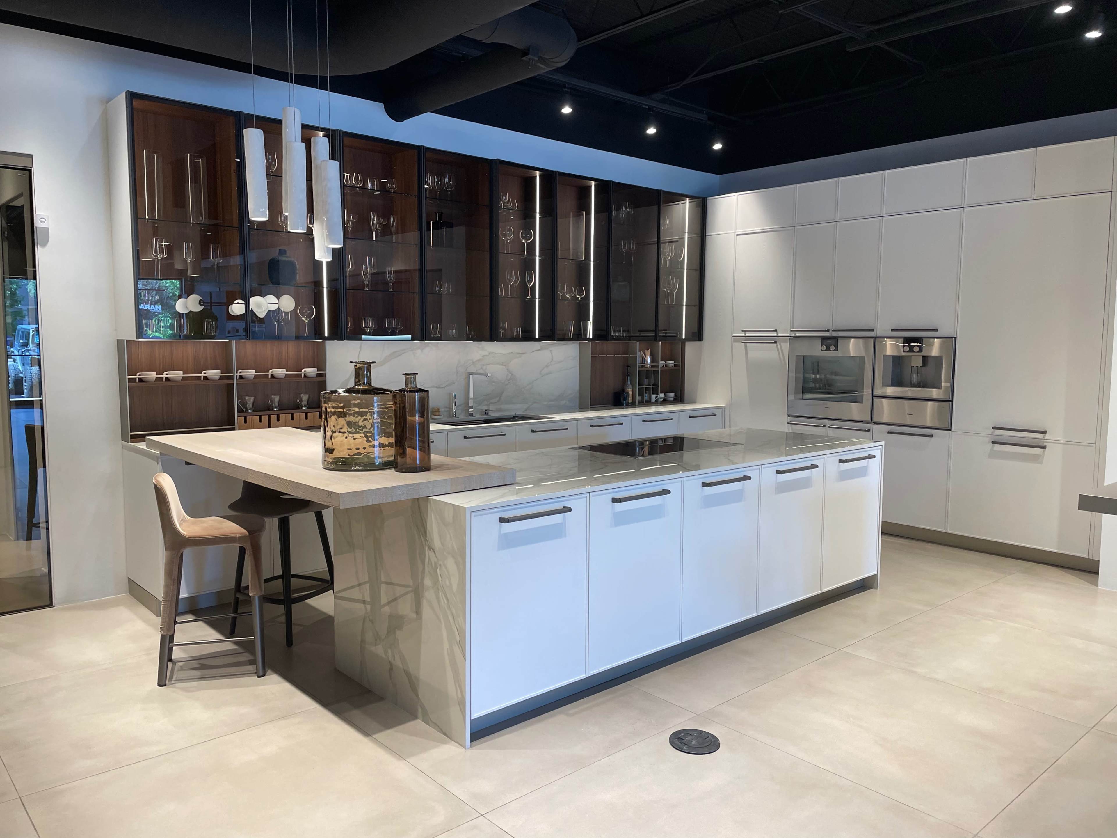 A modern kitchen display with a large island, minimalist cabinetry, and stainless steel appliances.