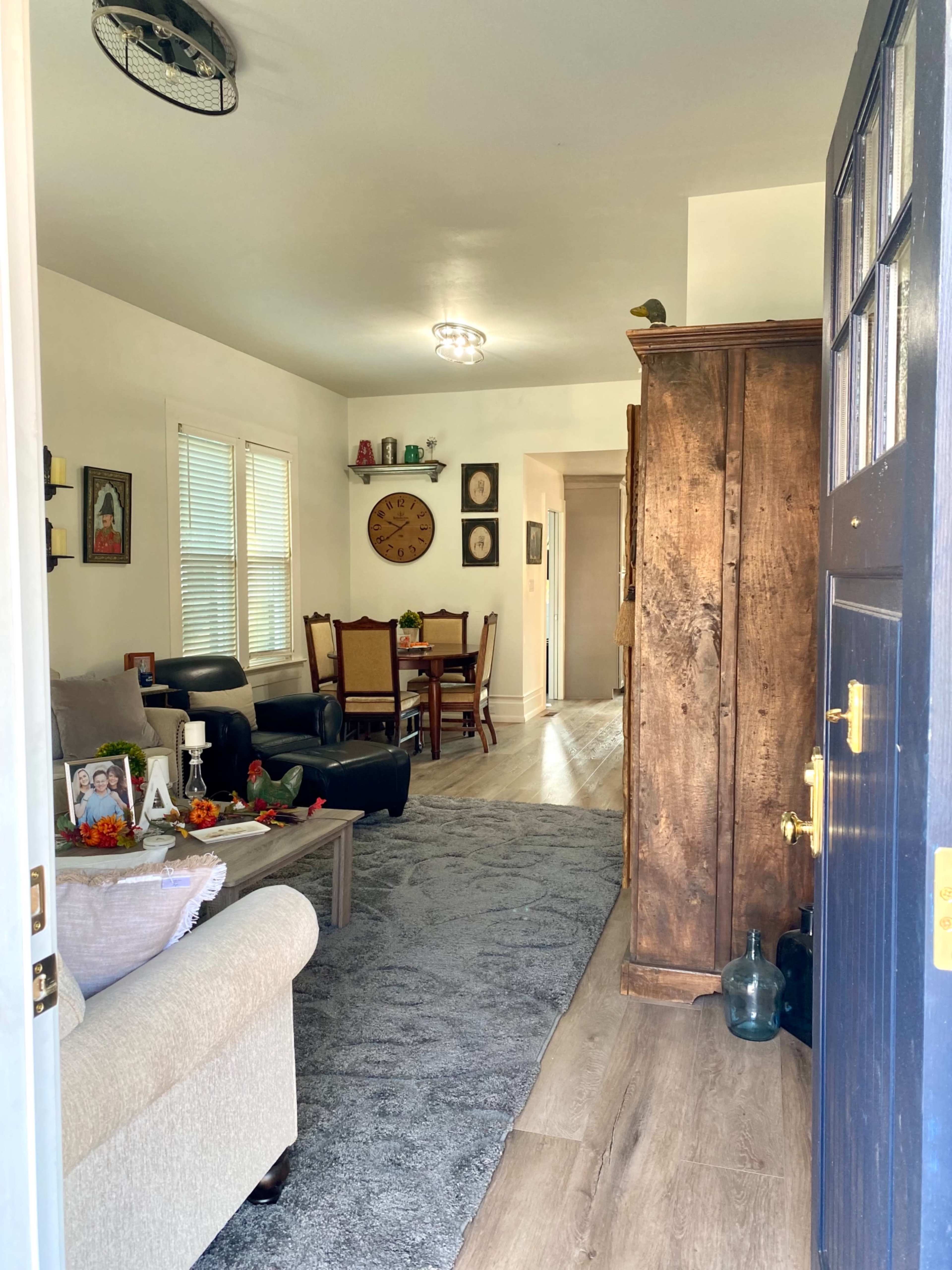 The entrance to a cozy living space featuring a sofa, dining area, and decorative accents, as viewed from an open door.