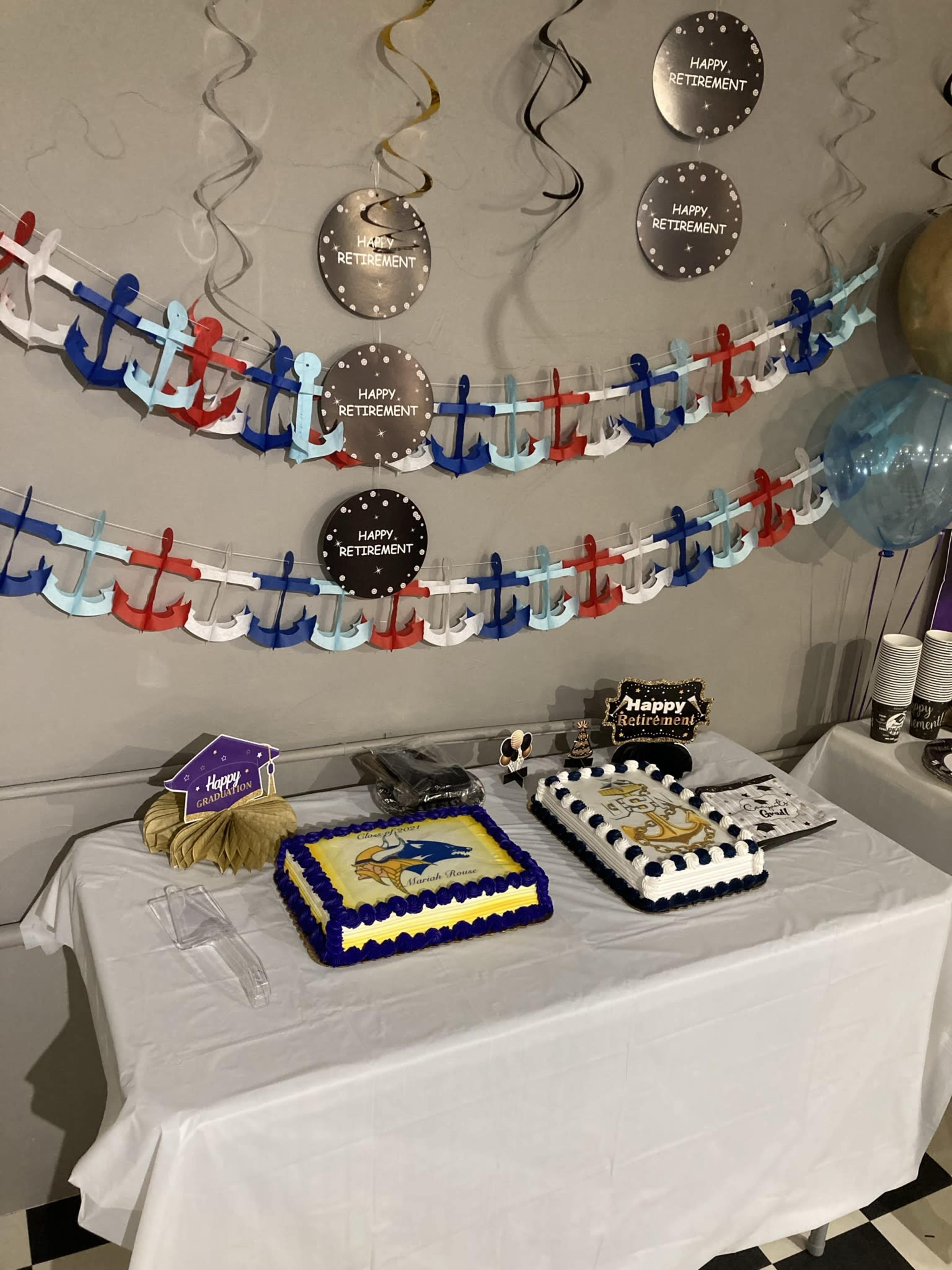 A decorated table features two retirement-themed cakes, along with festive decorations including banners and balloons.
