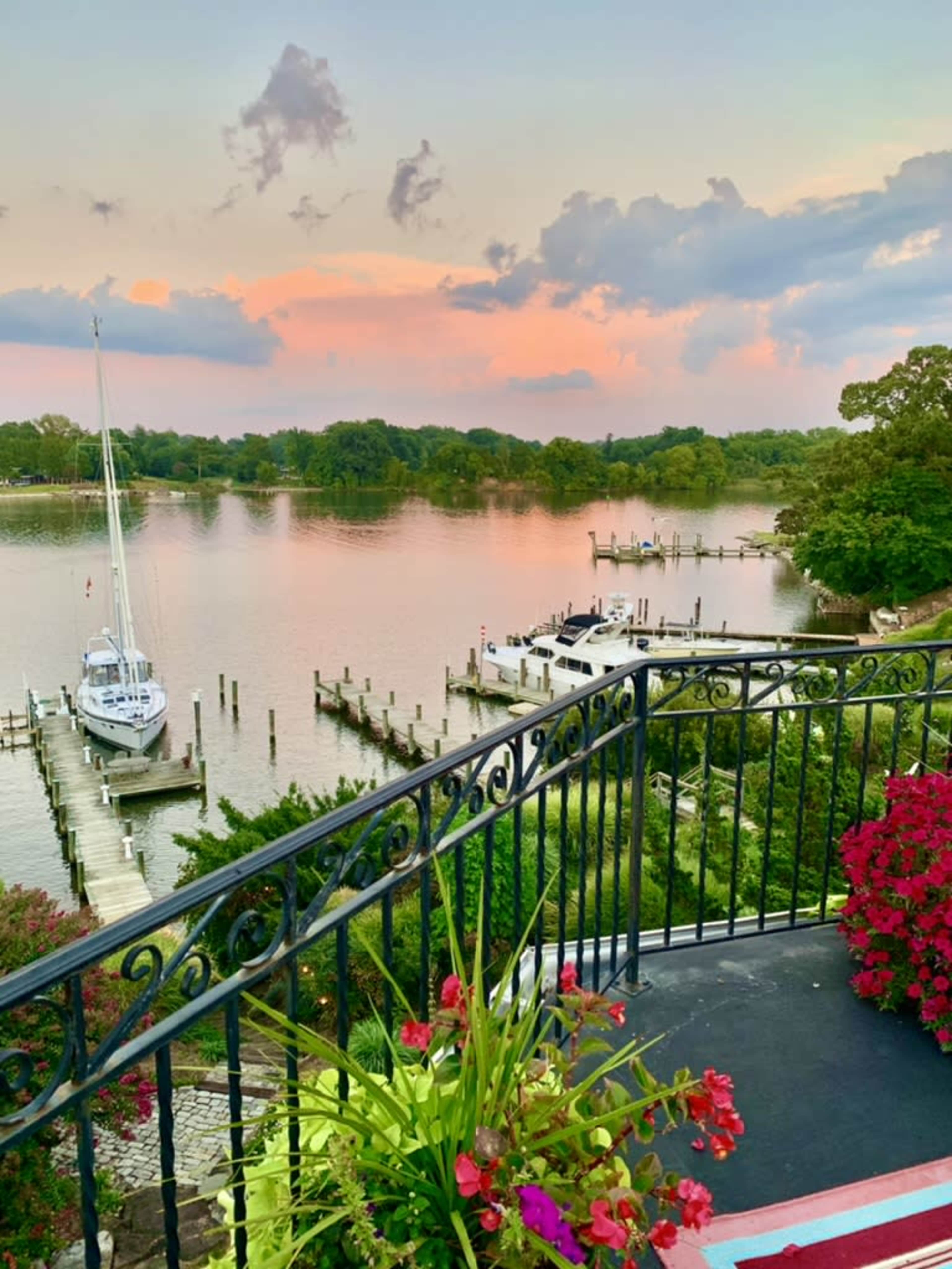 A serene waterfront scene showcases boats docked on a calm river under a pastel sunset sky.