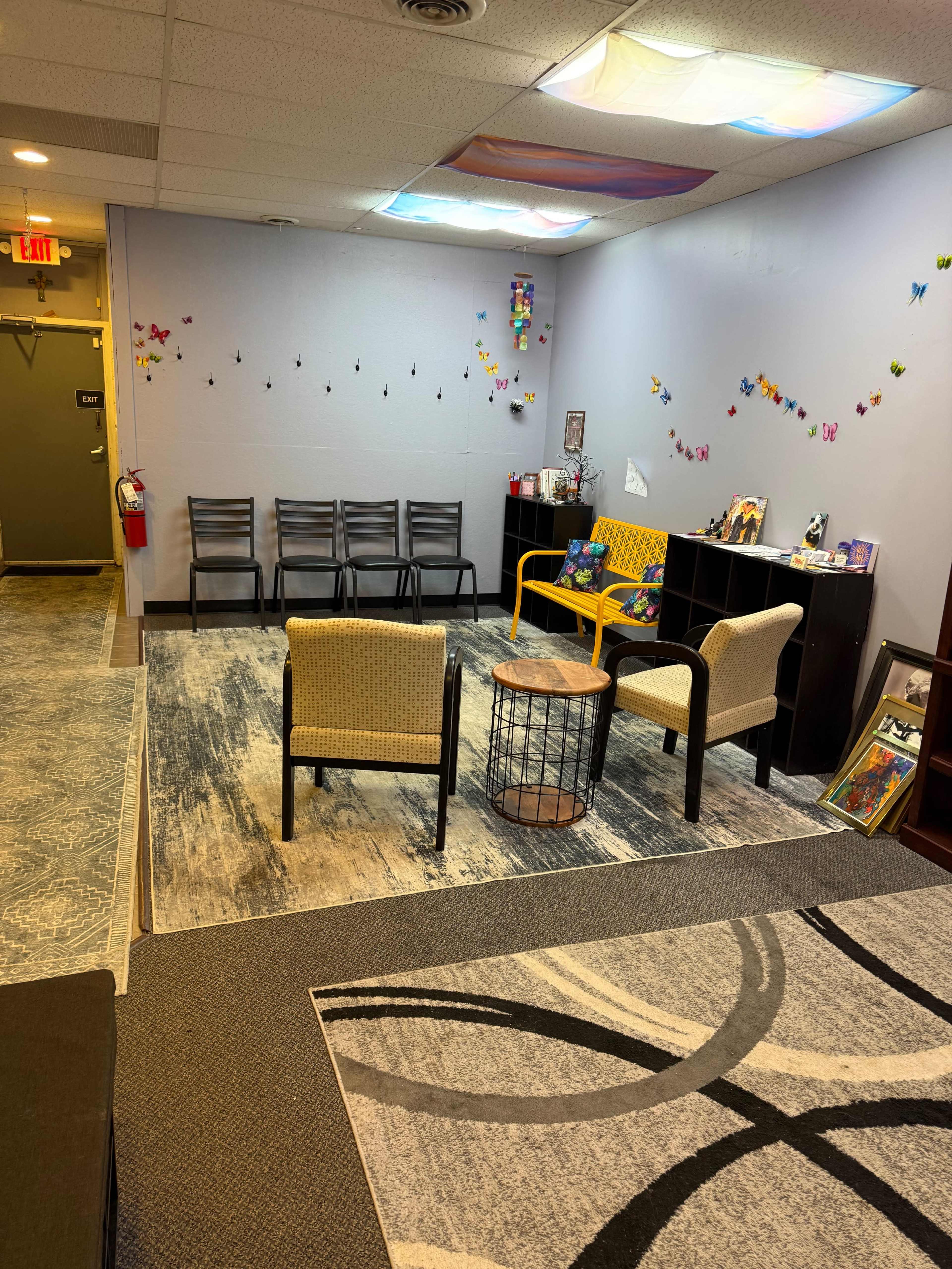 The image shows a waiting room with chairs, a coffee table, and decorative butterflies on the walls.