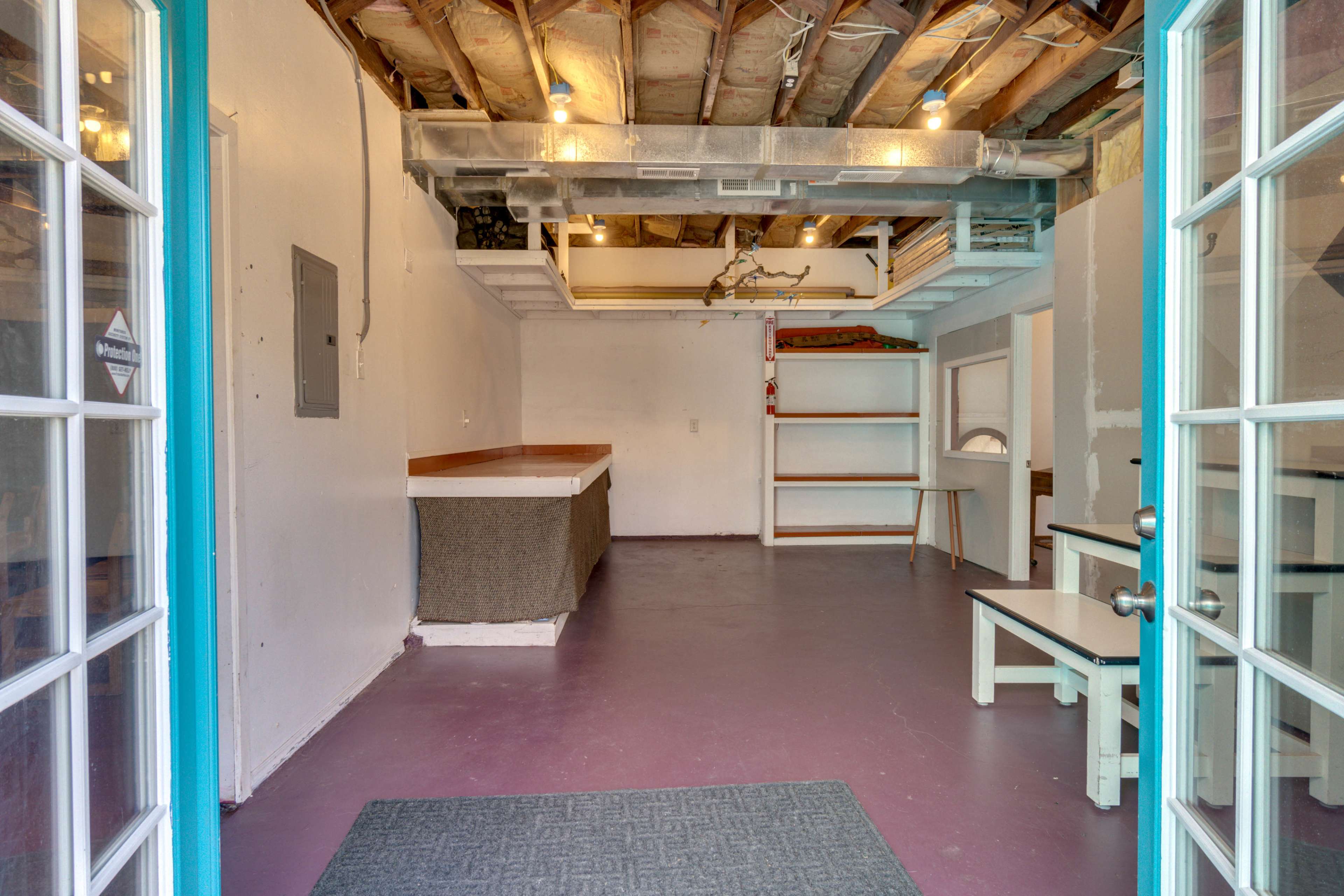 A spacious, unfinished interior with exposed beams, a partial bar counter, and shelving units along the walls.