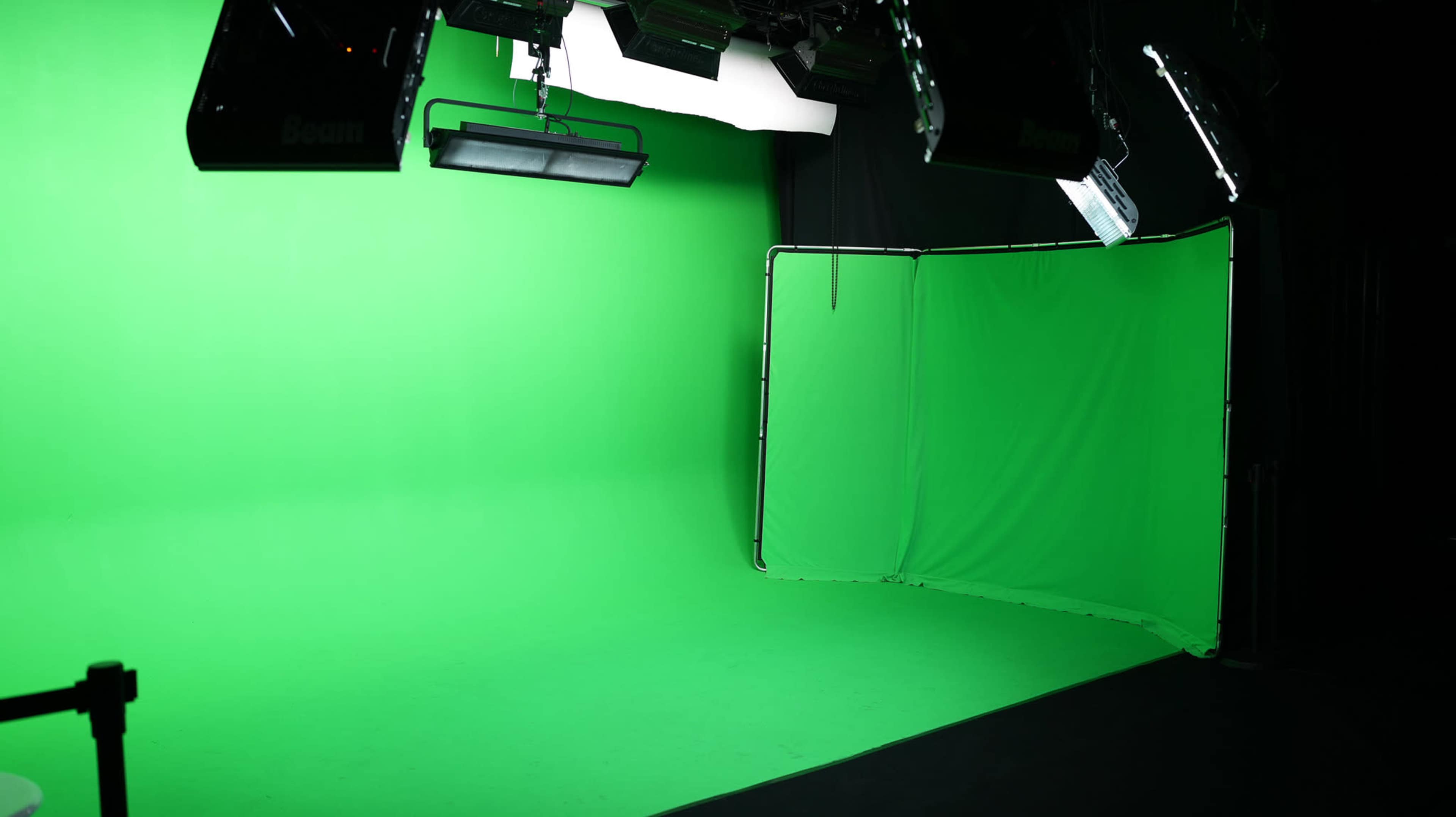 A green screen setup with lights positioned above and to the side in a studio environment.