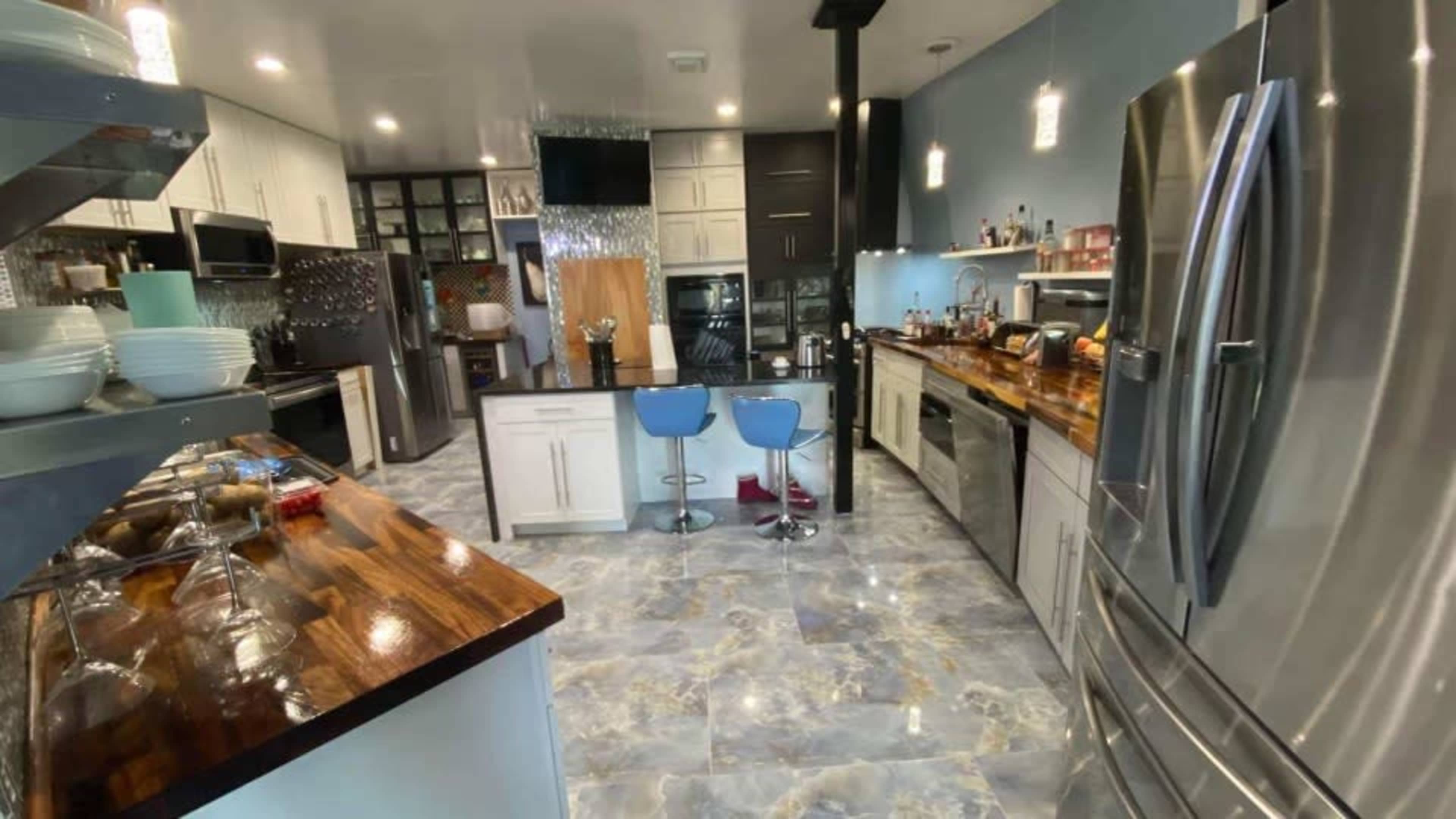 A modern kitchen with a combination of dark and light cabinetry, stainless steel appliances, and a central island with bar seating.